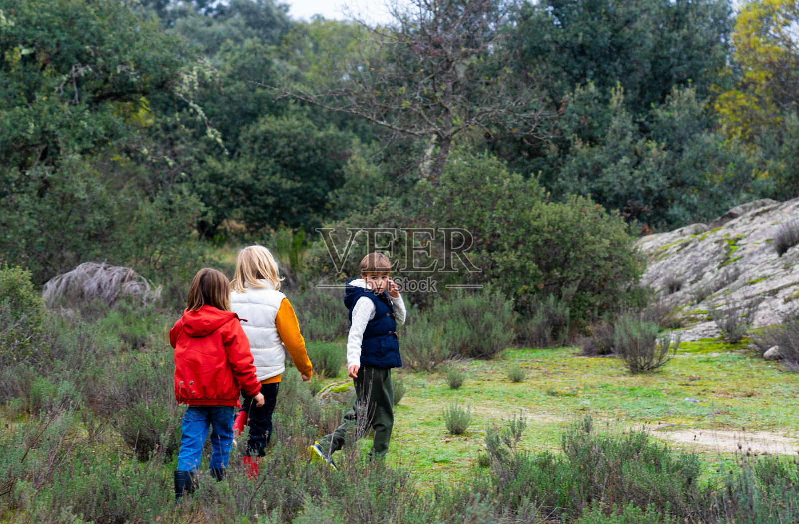 从后面看到三个孩子走过田野照片摄影图片