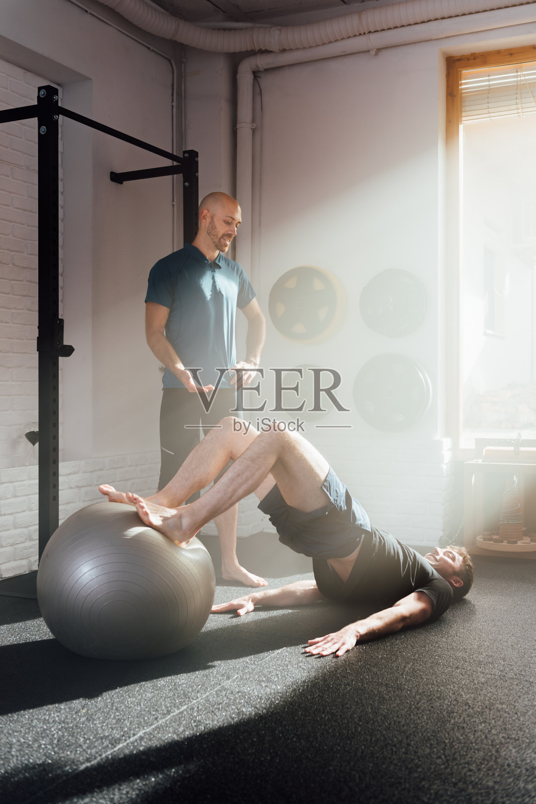 男子在教练的帮助下做臀部推举练习照片摄影图片