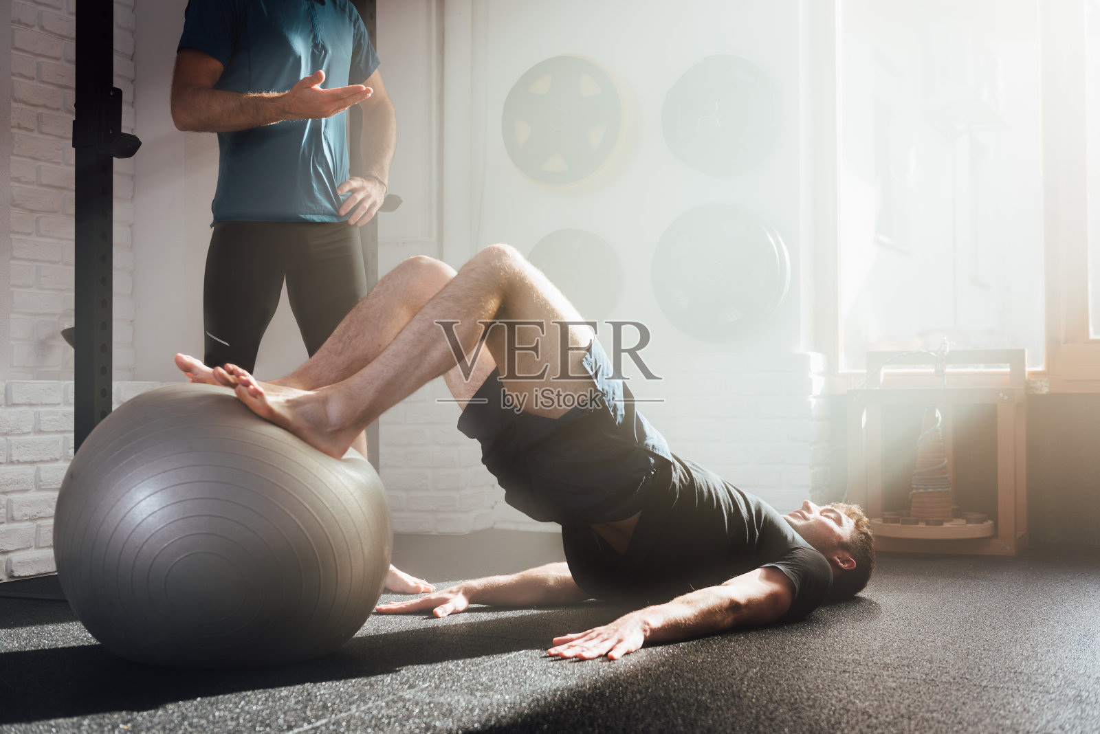 男子在不知名教练的帮助下做臀部推举练习照片摄影图片