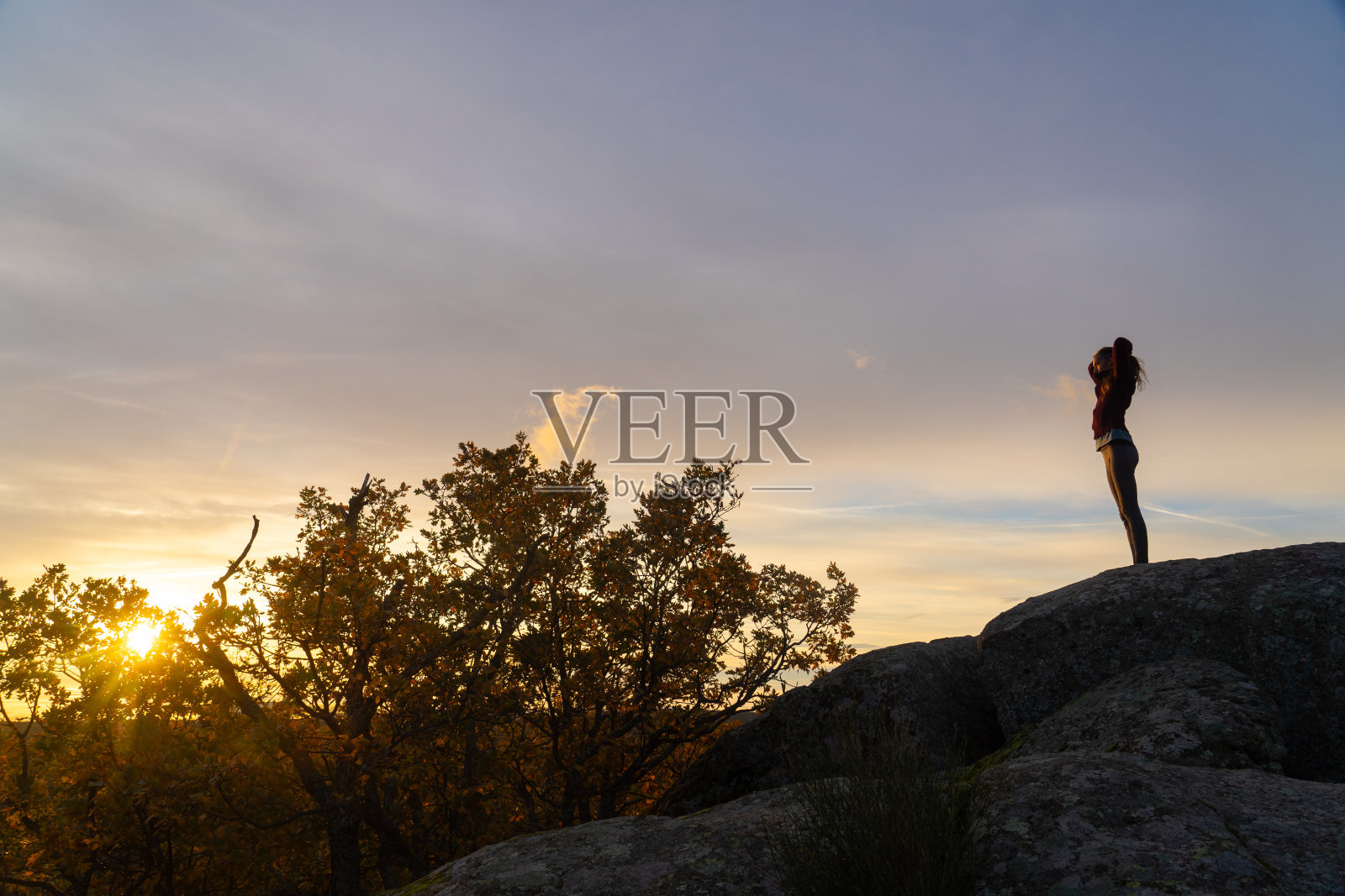 日出时分,一个女人在山顶上扎着马尾辫照片摄影图片