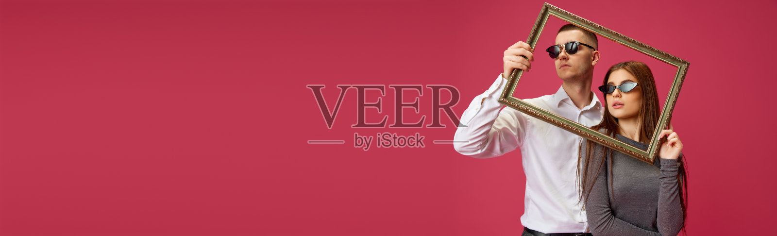 年轻夫妇的肖像,男人和女人,在粉红色的工作室背景下用相框摆姿势。情人节,恋爱照片摄影图片