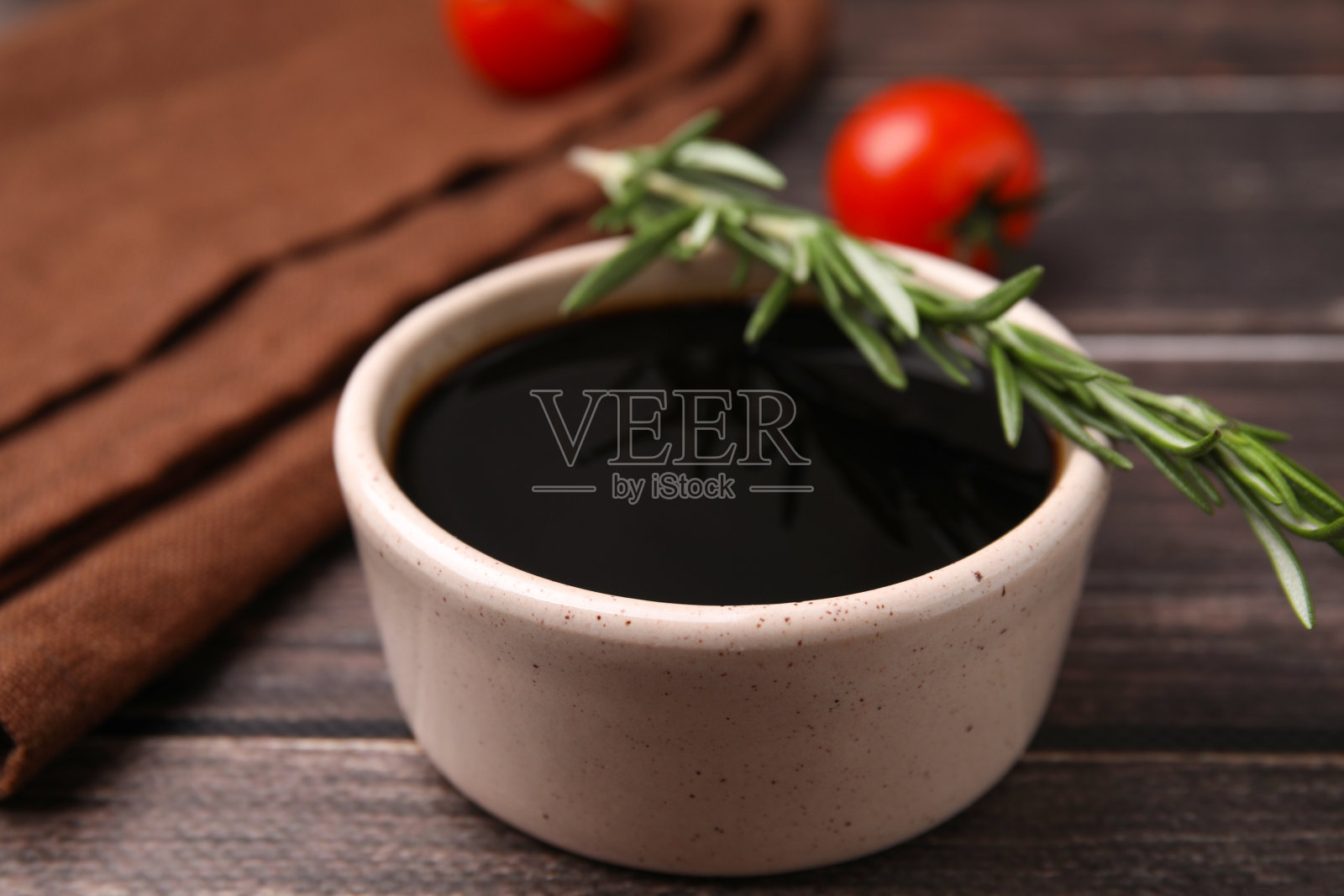 木桌上有一碗香醋,迷迭香和西红柿,特写照片摄影图片