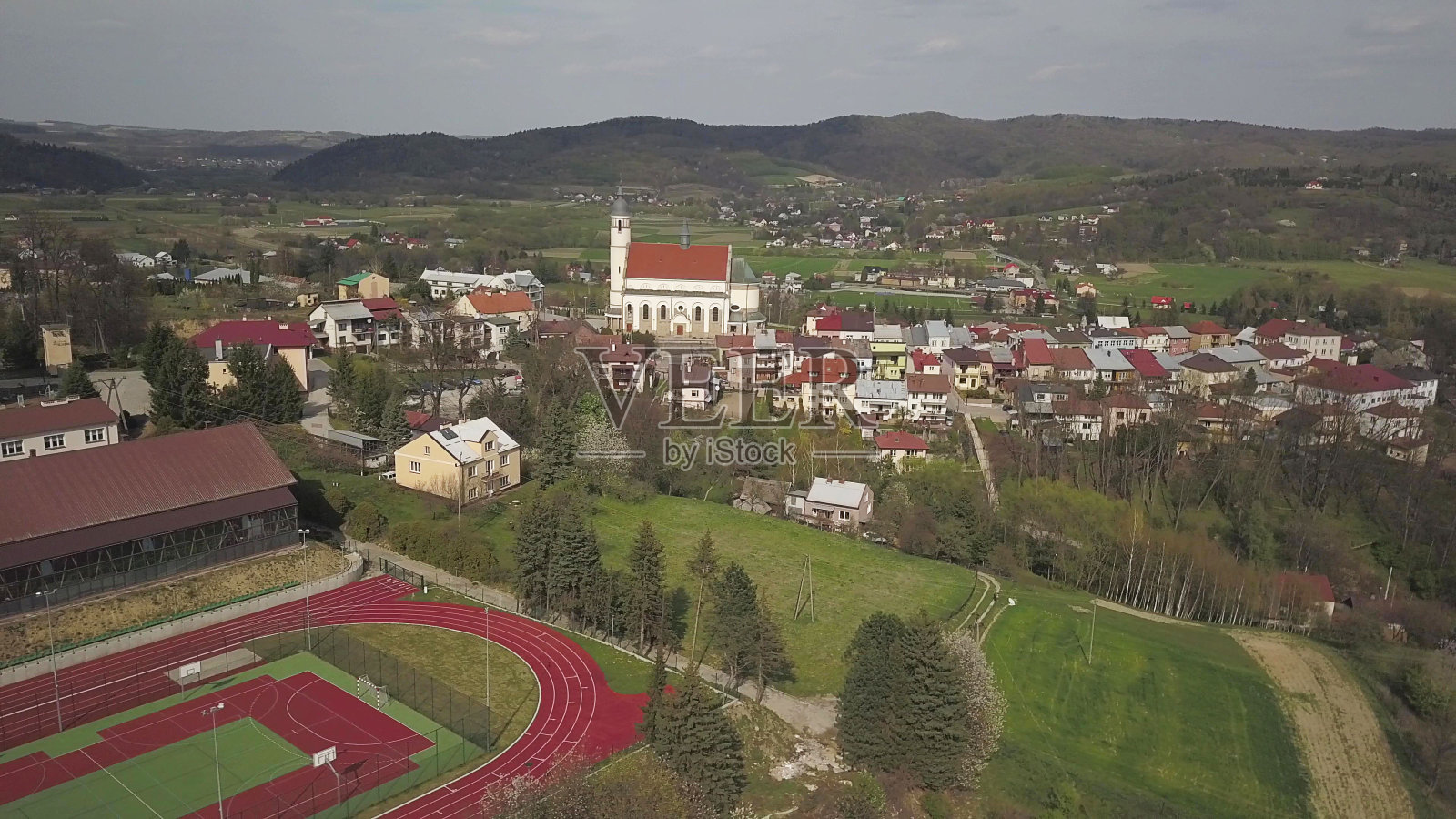 波兰,弗莱什塔克- 2019年8月8日:中世纪的欧洲城市弗莱什塔克,校园内有一座现代化的体育场。航拍与无人机或四旋翼机。在运动场地跑步的年轻人。慢跑照片摄影图片