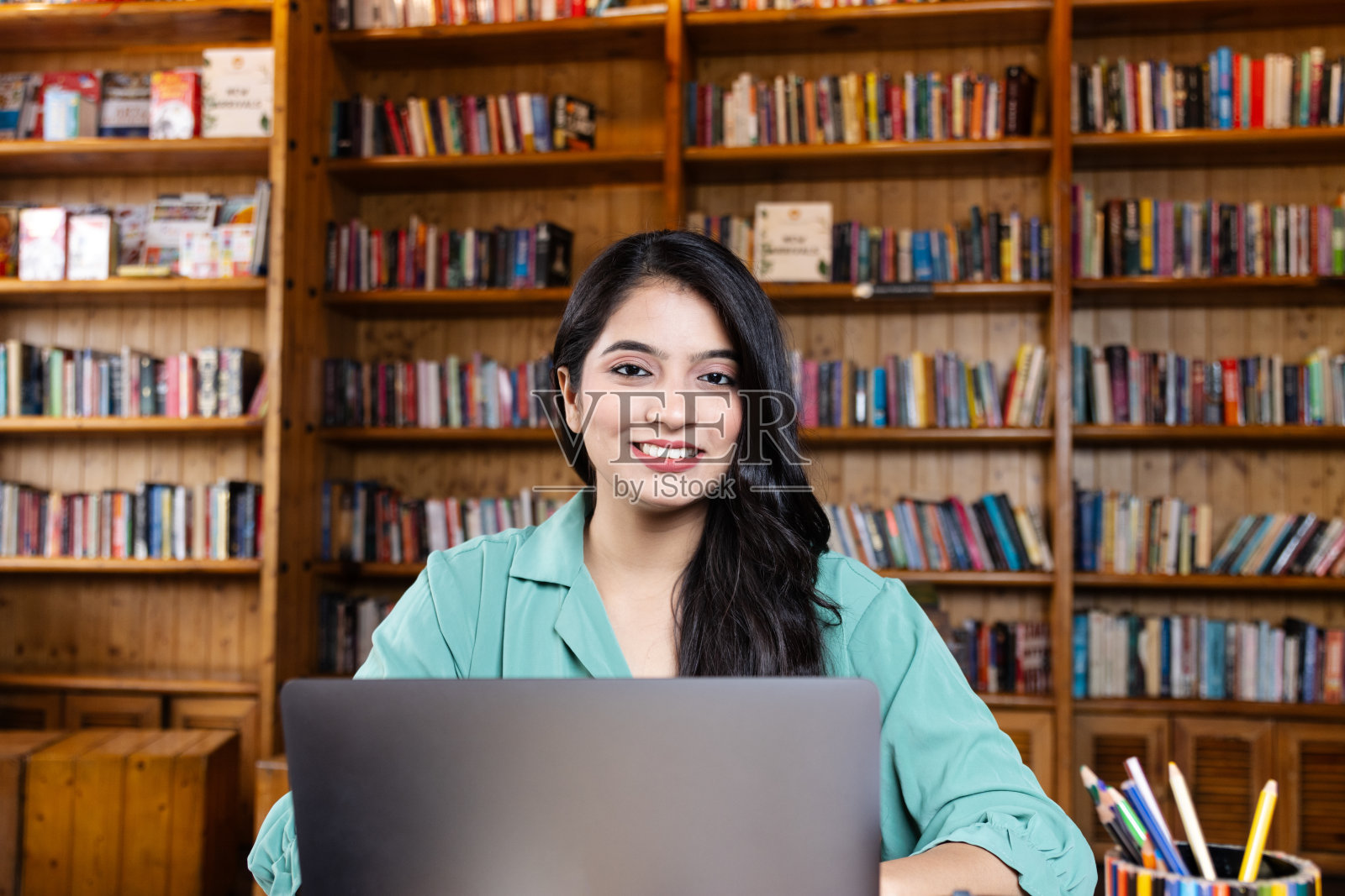 漂亮的年轻女商人,在学校或大学图书馆的笔记本电脑上学习或解释视频电话,或在公司办公室工作,在互联网或书籍上搜索信息照片摄影图片