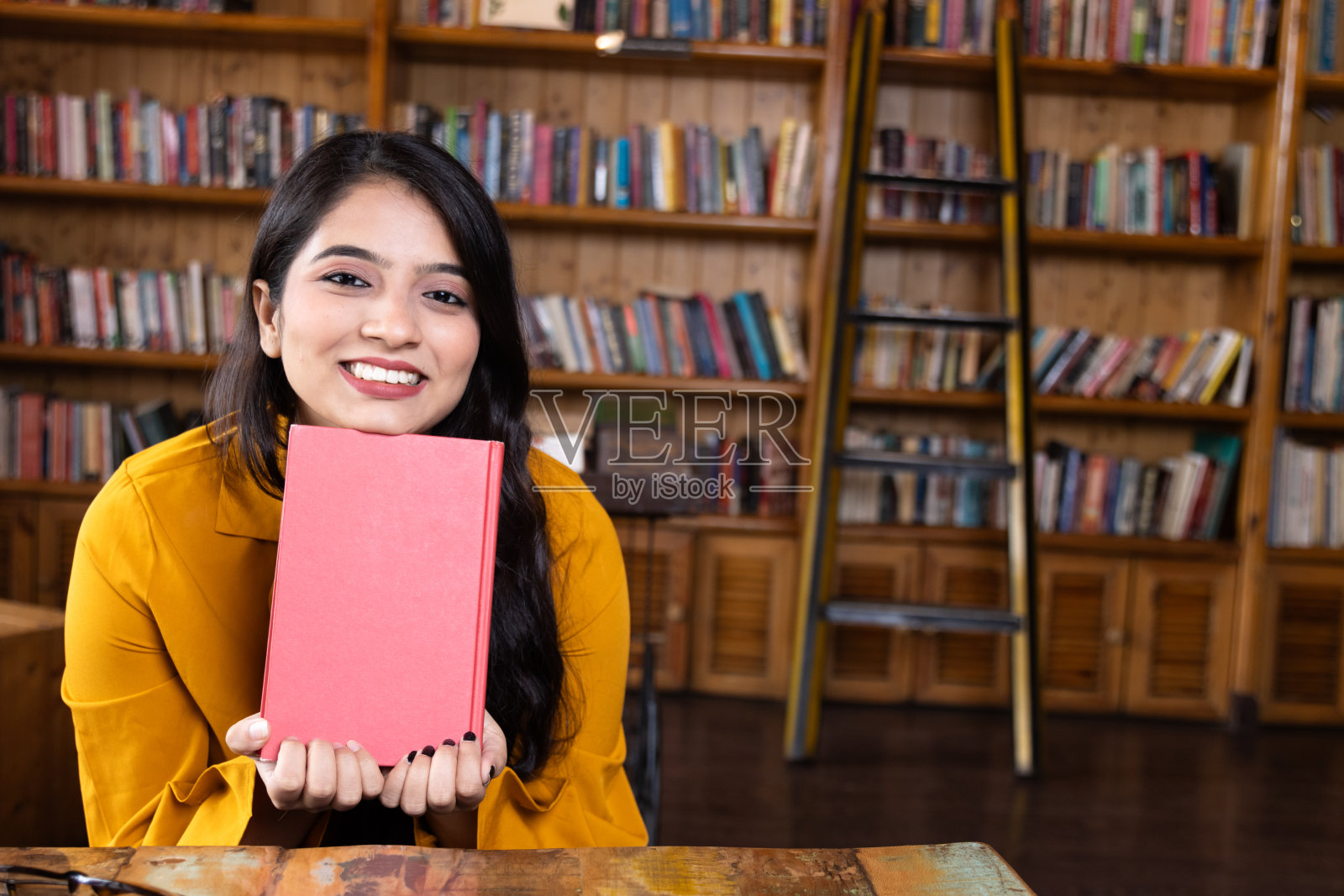 一个漂亮的年轻女孩,商人或学生,在学校或大学图书馆或办公室拿着一本书工作或学习照片摄影图片