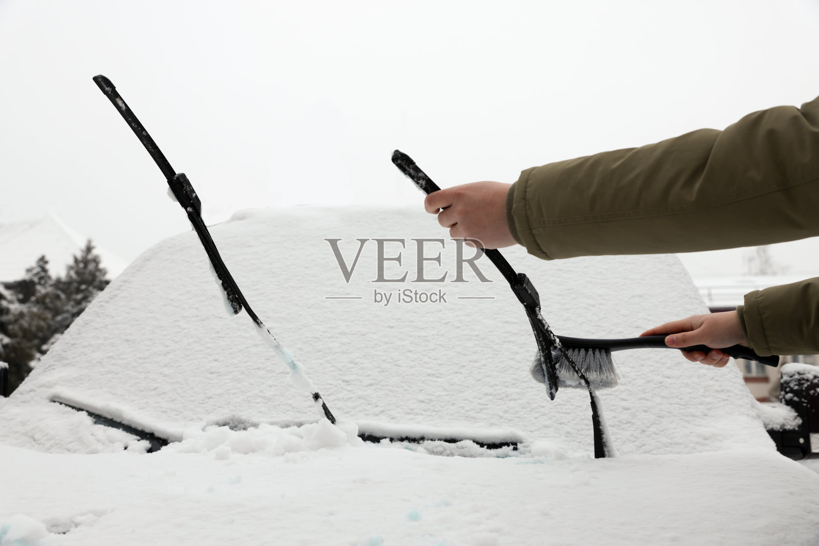 一名妇女在户外用刷子清理汽车雨刷片上的雪,特写照片摄影图片