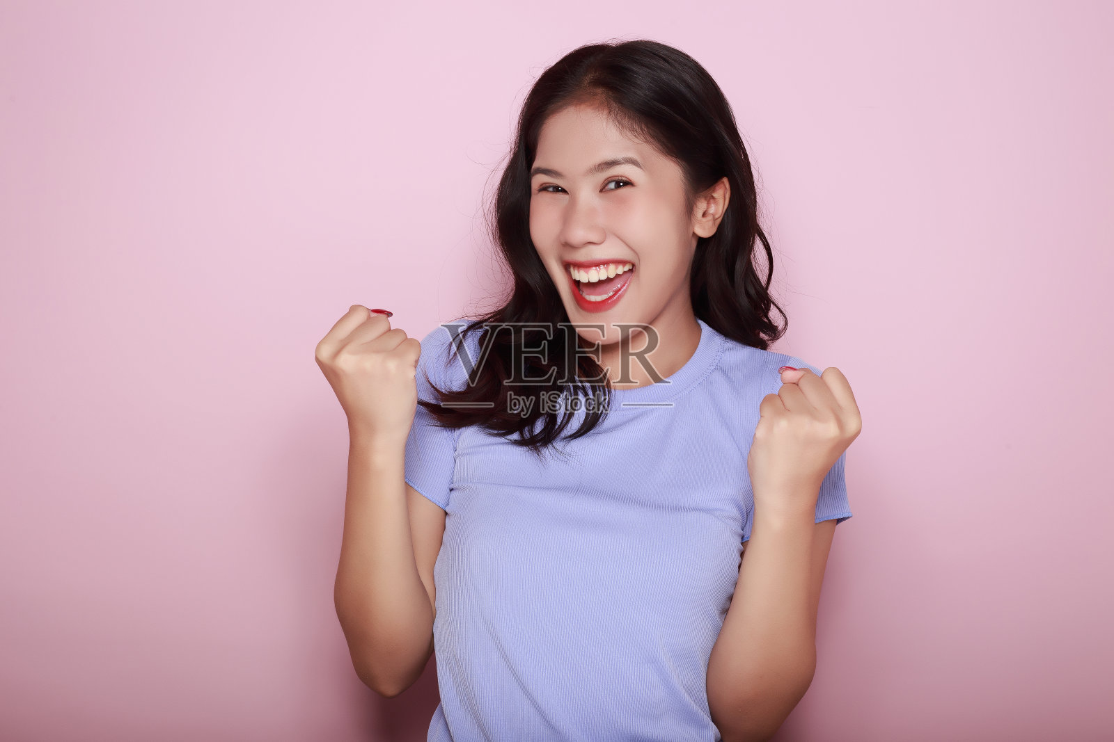 一个亚洲女人摆着愉快的姿势,一个友好的年轻女人微笑的肖像,一个美丽的年轻女人在浅粉色背景的肖像,照片摄影图片