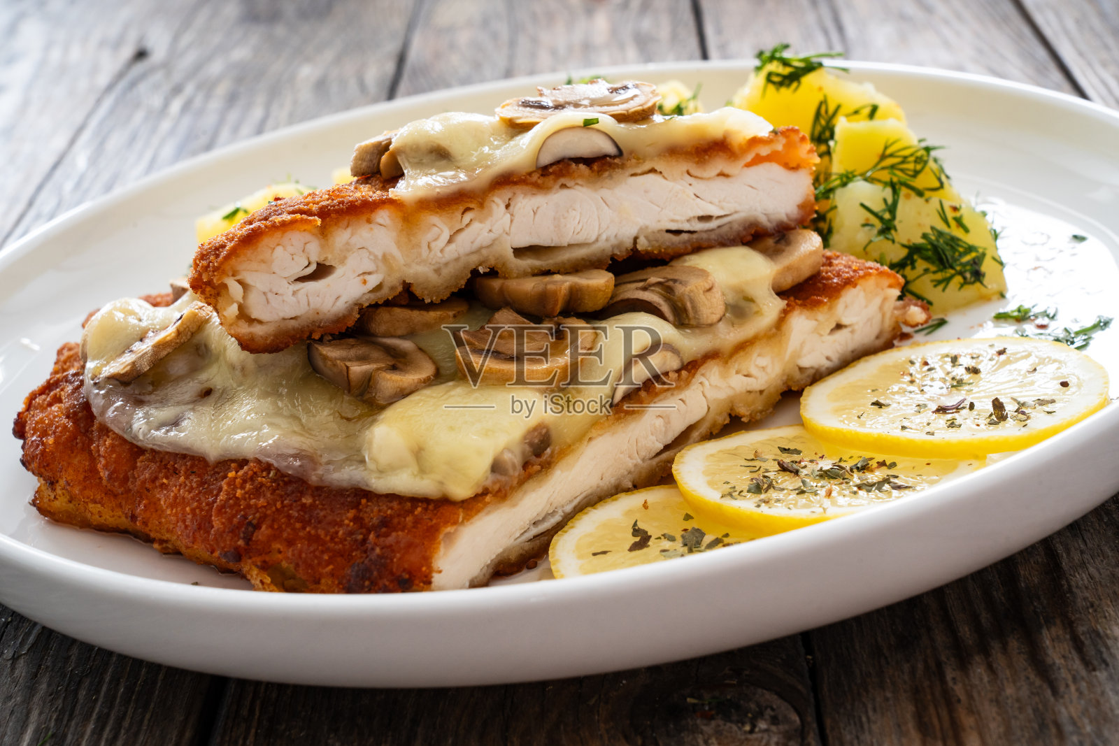 木桌上面包屑烤鸡排配芝士、白蘑菇和煮土豆照片摄影图片