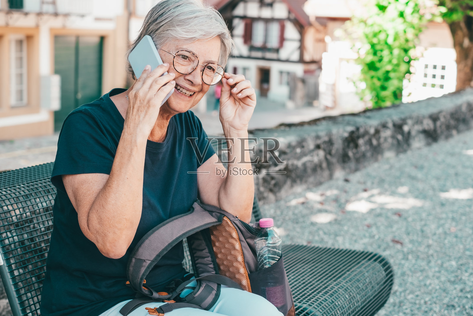 快乐的老年妇女坐在户外讲手机,老太太享受自由和假期使用智能手机连接照片摄影图片