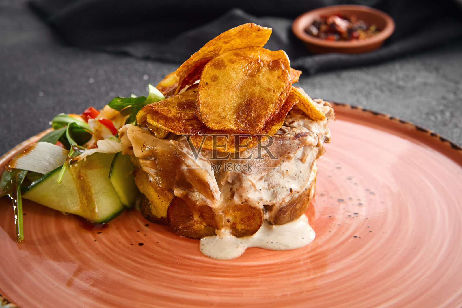 多汁的牛肉奖章包在培根里,配上酥脆的薯条和新鲜的蔬菜沙拉,艺术地放在一个圆形盘子里,背景是黑色的照片摄影图片