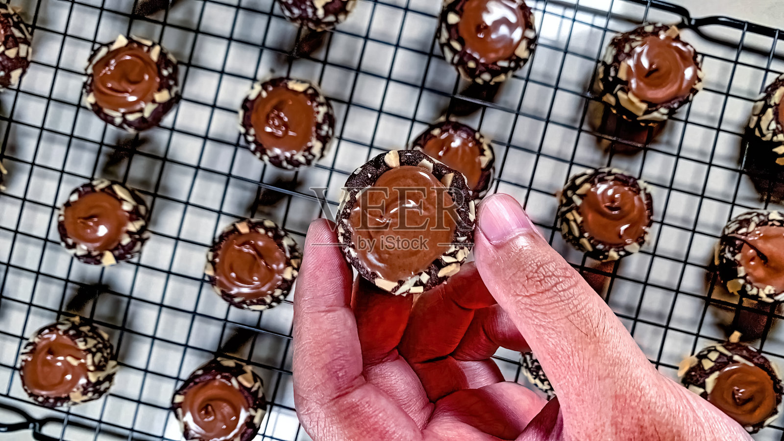 一只手拿着一个迷你巧克力饼干,在几个迷你巧克力饼干的背景上撒上燕麦片照片摄影图片