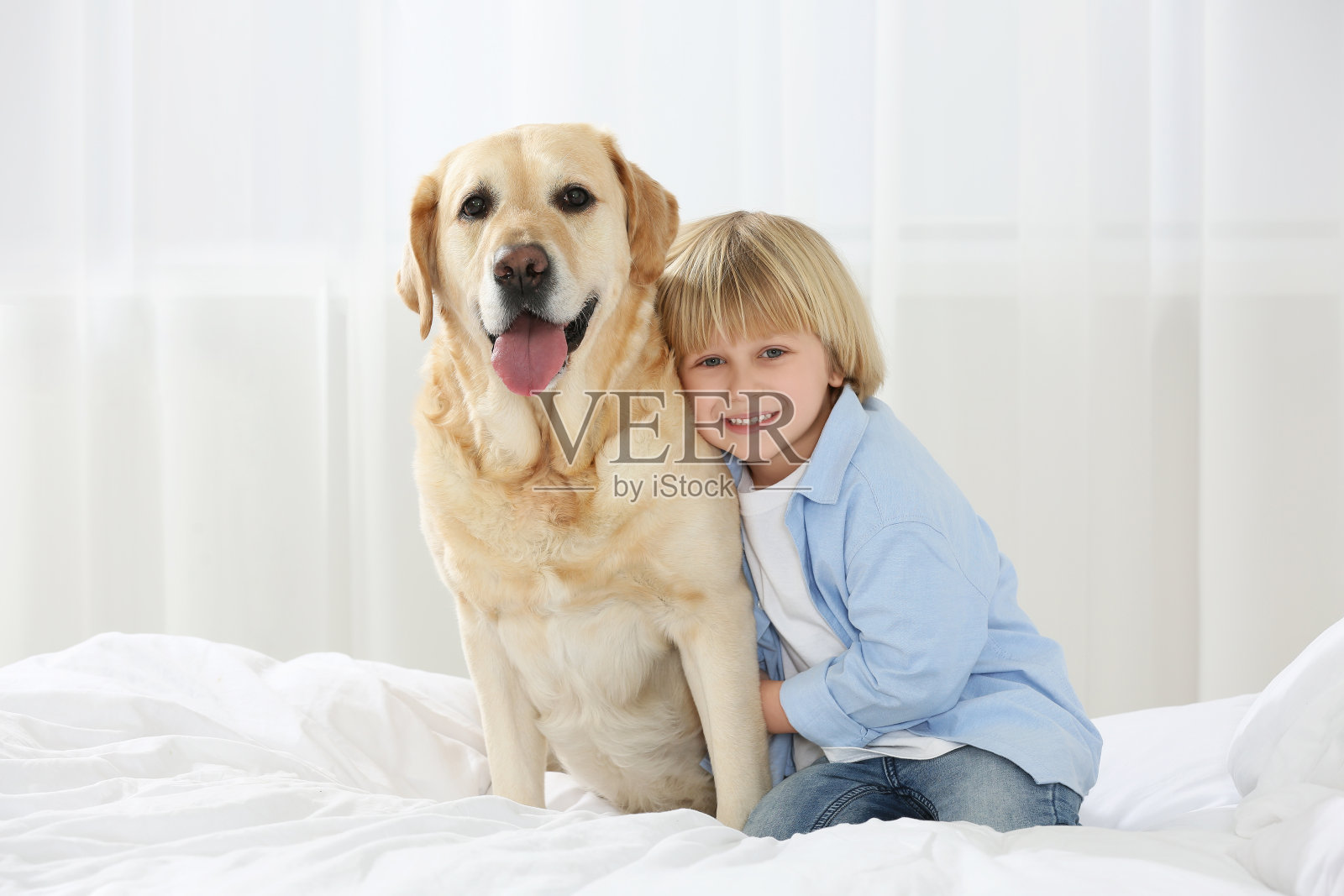 可爱的小孩和金毛猎犬躺在家里的床上。可爱的宠物照片摄影图片