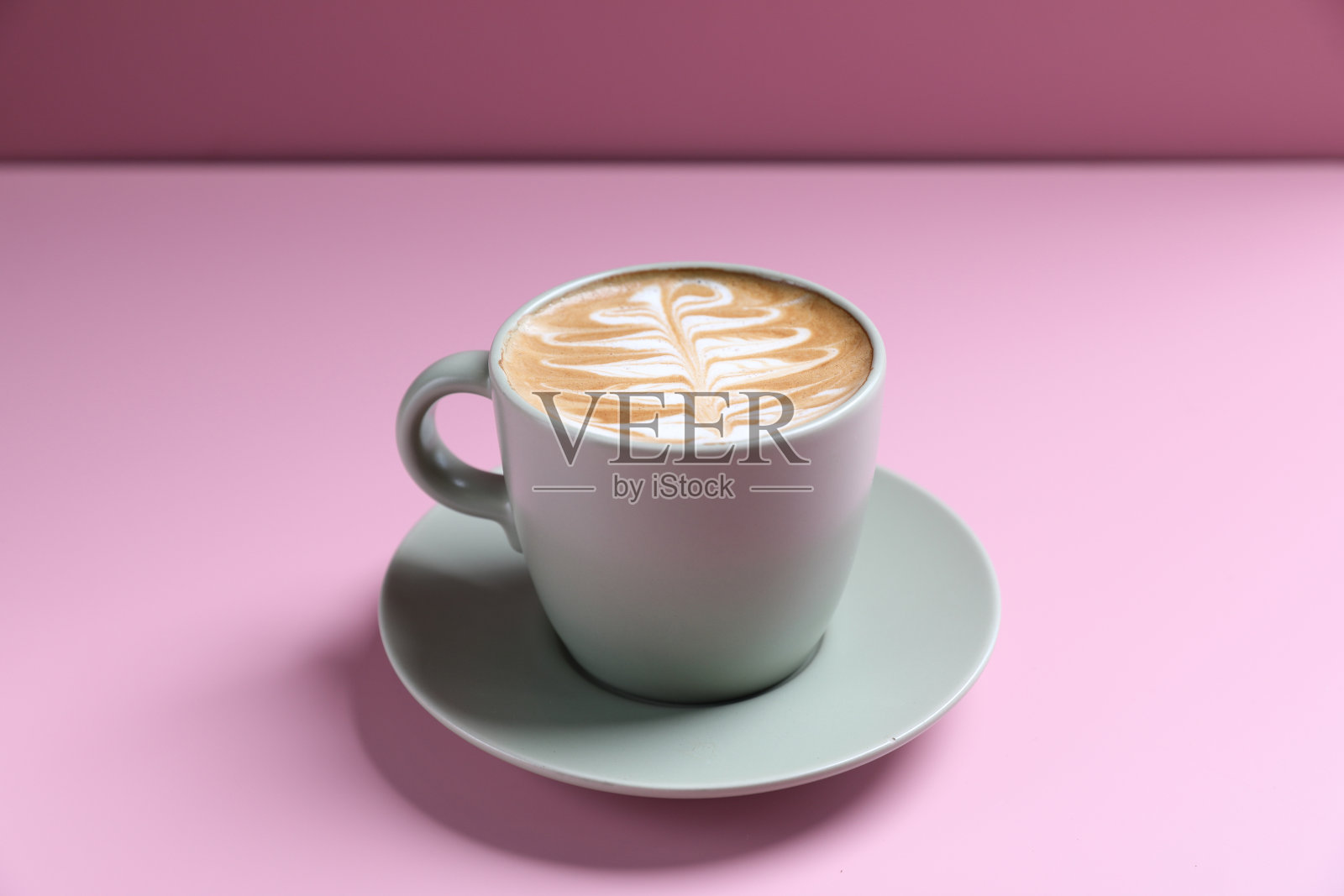 热卡布奇诺与拉花艺术隔离在粉红色的背景照片摄影图片