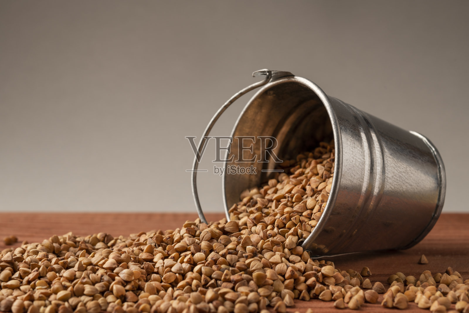 把荞麦倒进一个木制盘子里。荞麦是一种健康食品和膳食补充剂。照片摄影图片