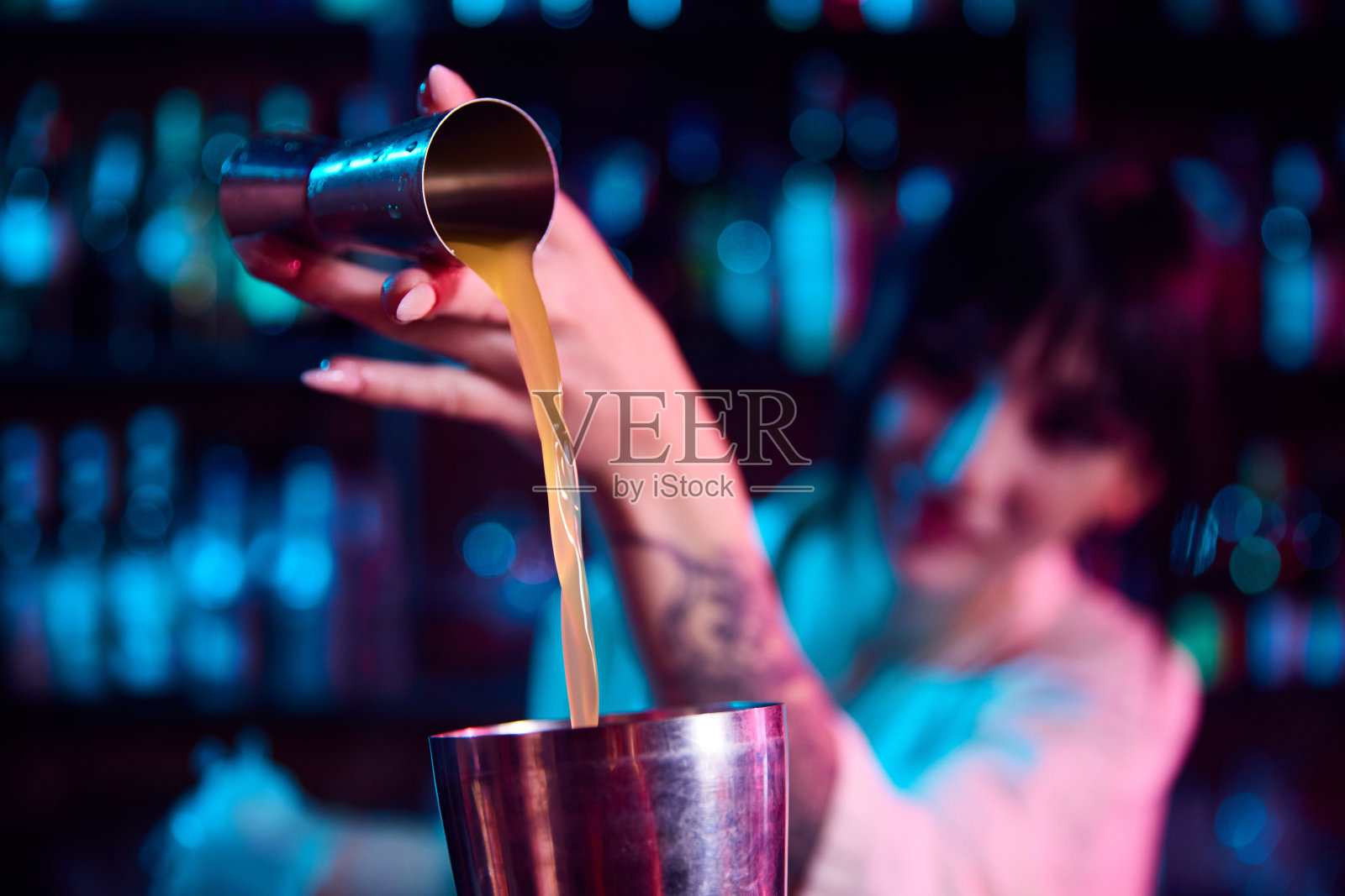 年轻漂亮的女人,调酒师调制鸡尾酒,在酒吧工作,把搅拌器里的酒倒进摇酒器,混合配料照片摄影图片