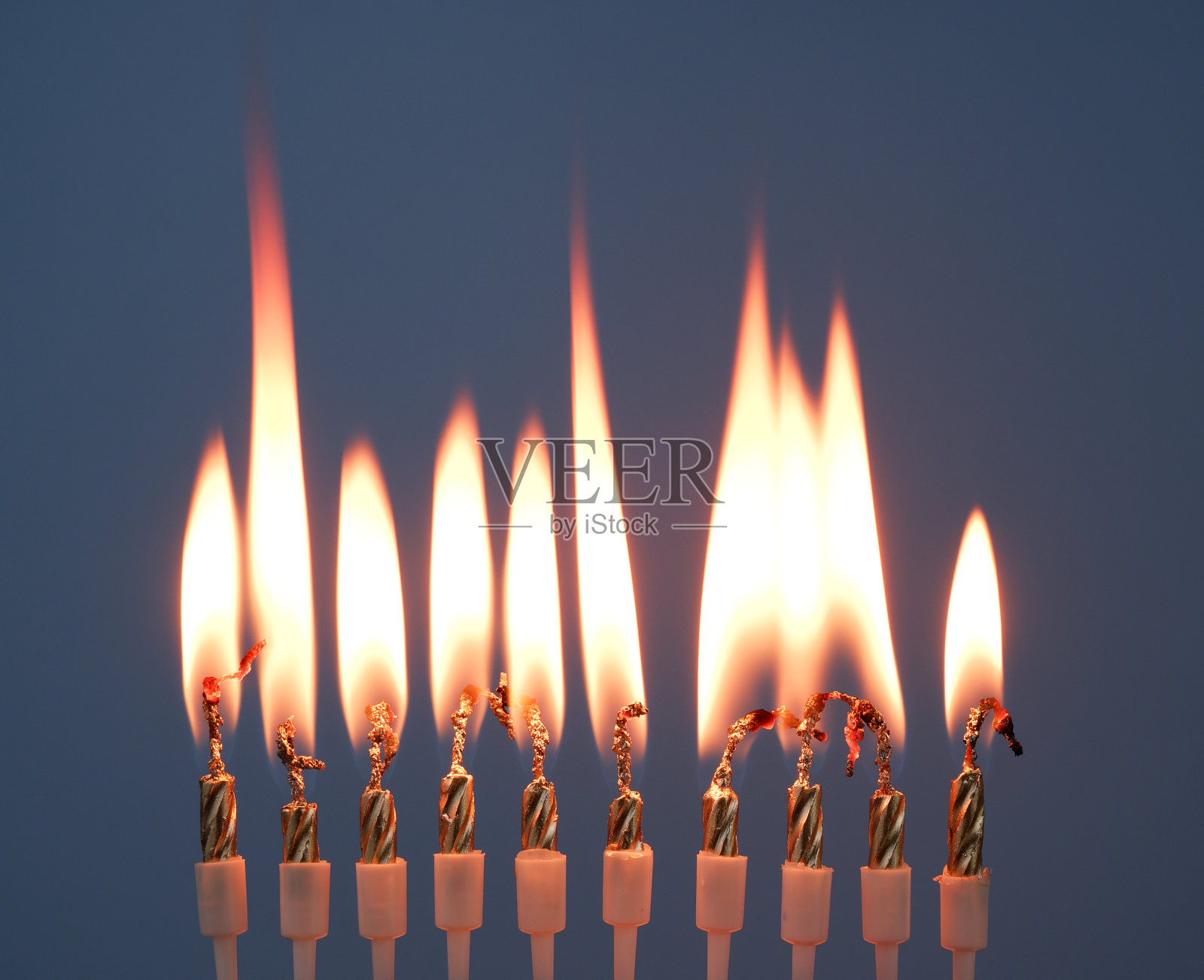 金色生日蜡烛在蓝色背景上燃烧。照片摄影图片
