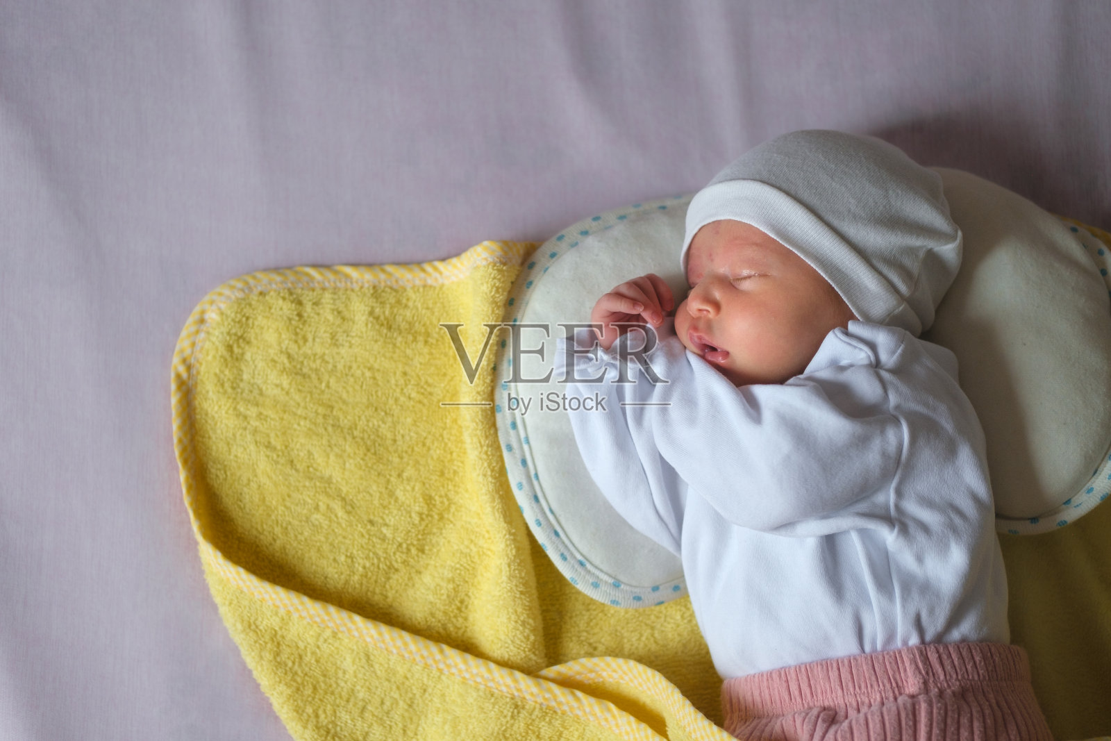 刚出生的婴儿独自在父母的床上香甜地睡著。照片摄影图片