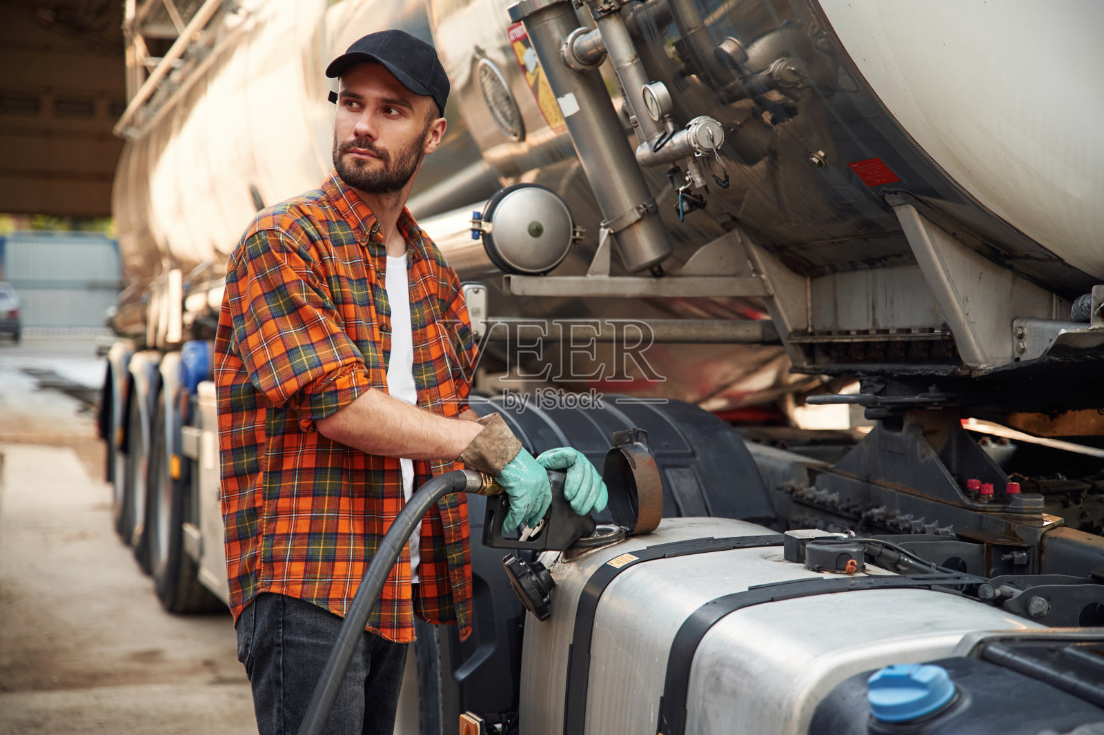 穿着便服的年轻卡车司机正在给车辆加油照片摄影图片
