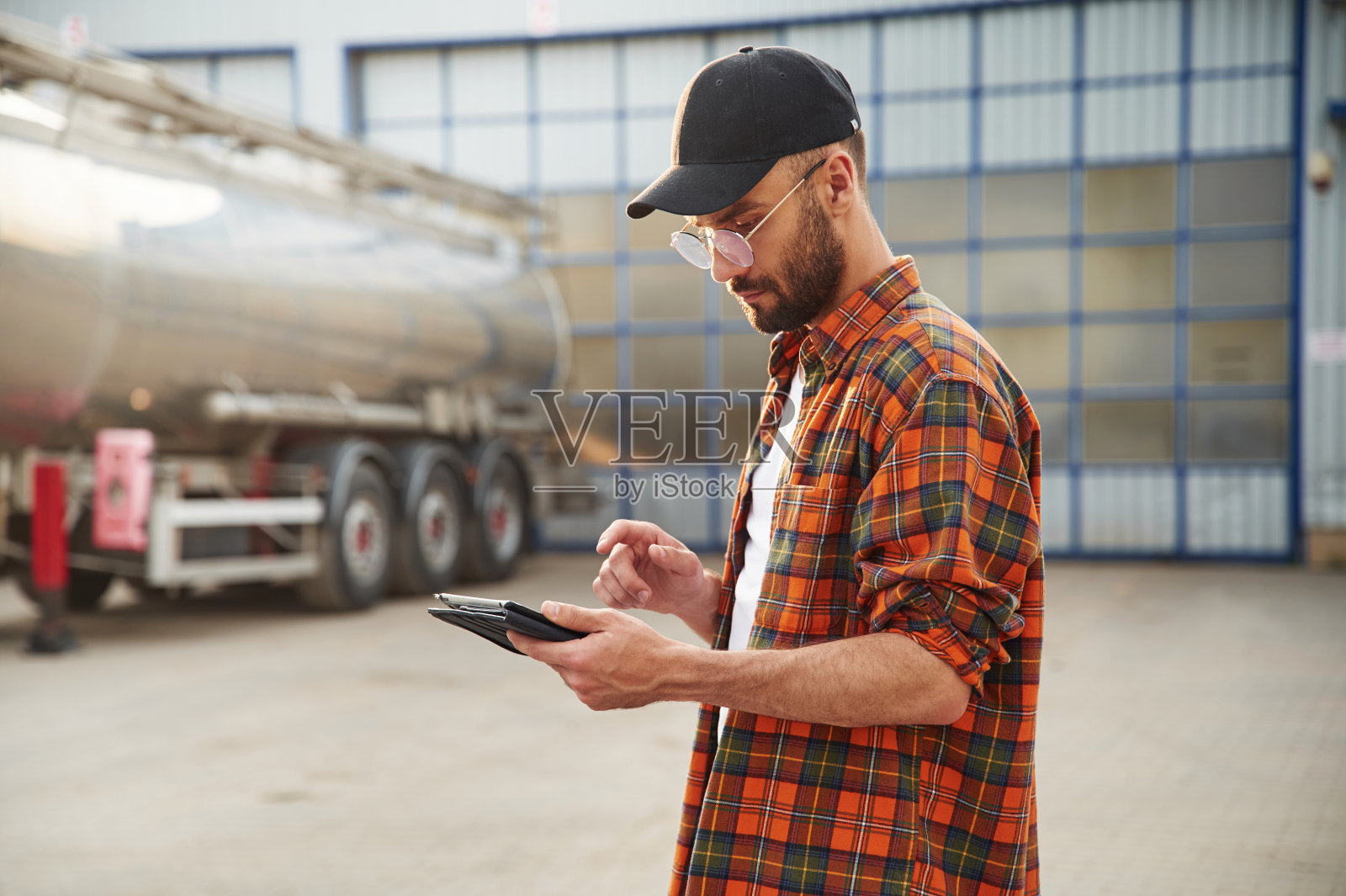 拿着平板电脑。穿着便服的年轻卡车司机照片摄影图片