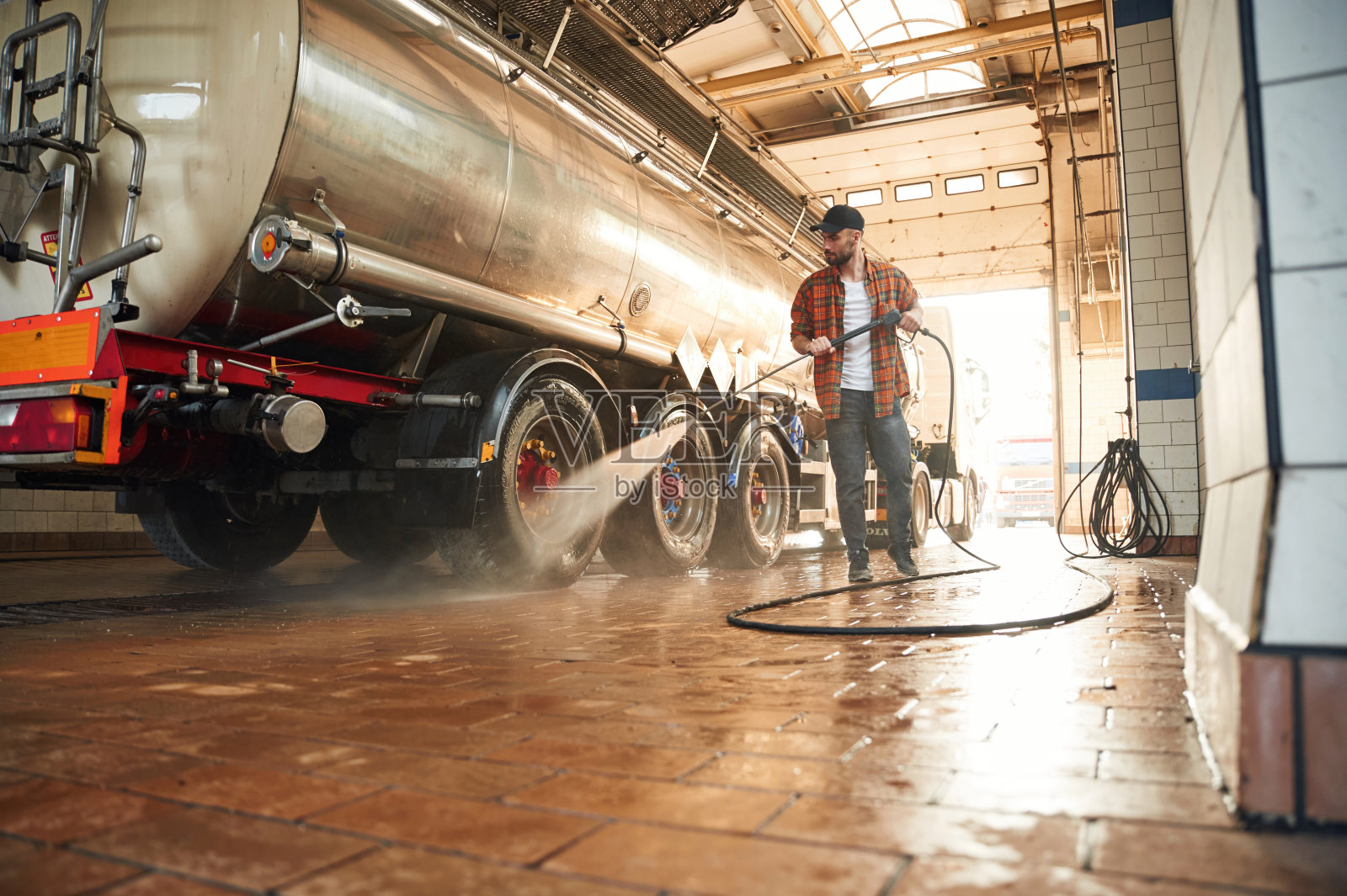 油罐车正在清洗。穿着便服的年轻卡车司机照片摄影图片