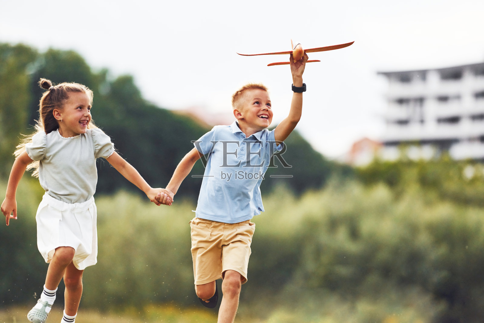 前视图。男孩和女孩在绿地上玩玩具飞机照片摄影图片