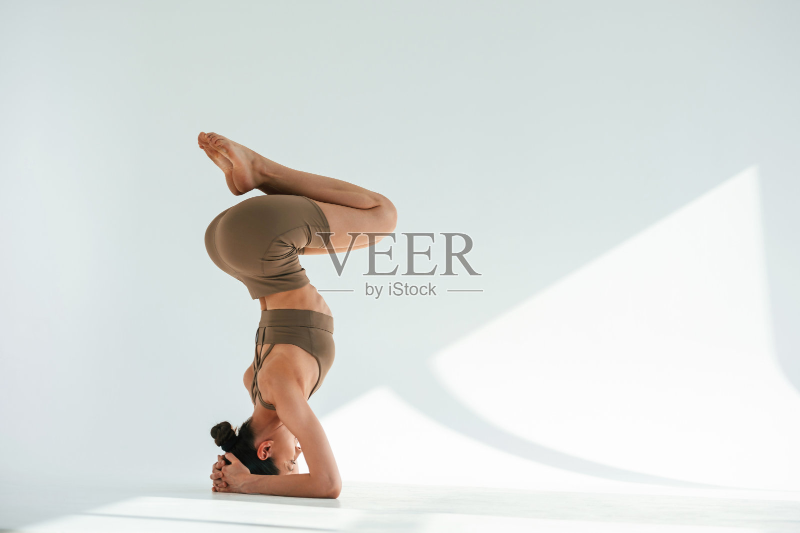 做倒立。身材苗条的年轻女子在演播室里穿着健身服照片摄影图片