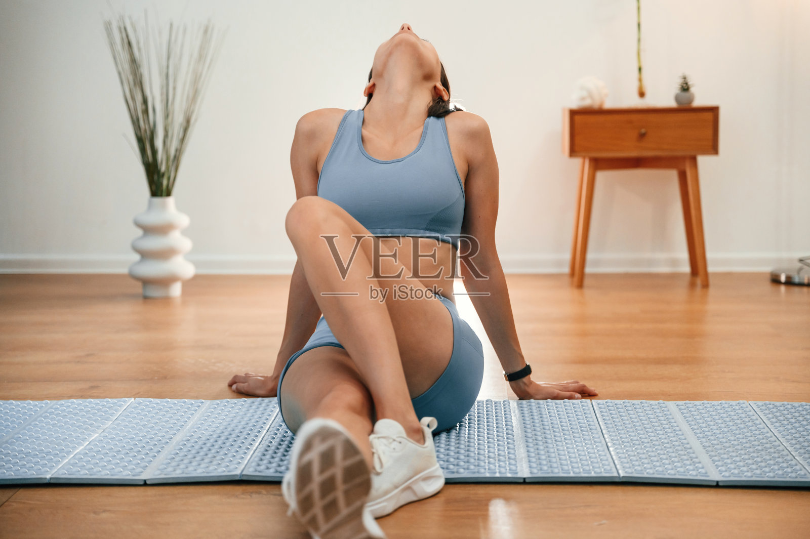 颈部练习。穿着运动服的漂亮女人在室内健身照片摄影图片