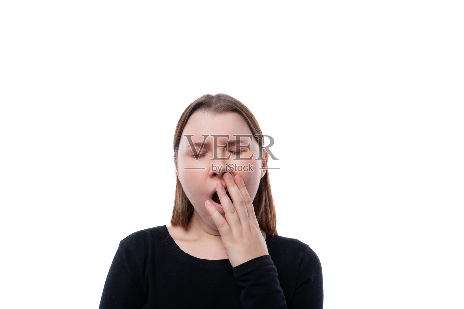 可爱的学龄女孩穿着黑色的衣服在白色的背景上打呵欠照片摄影图片