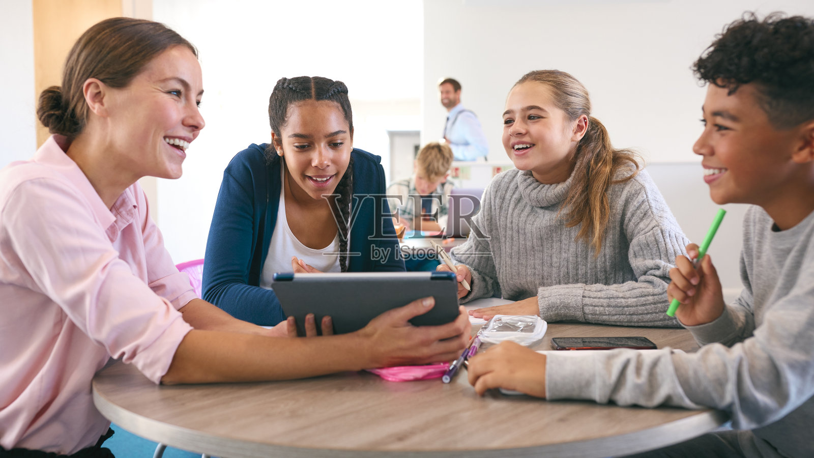 女中学或高中教师与学生一起在学习区域使用数字平板电脑照片摄影图片