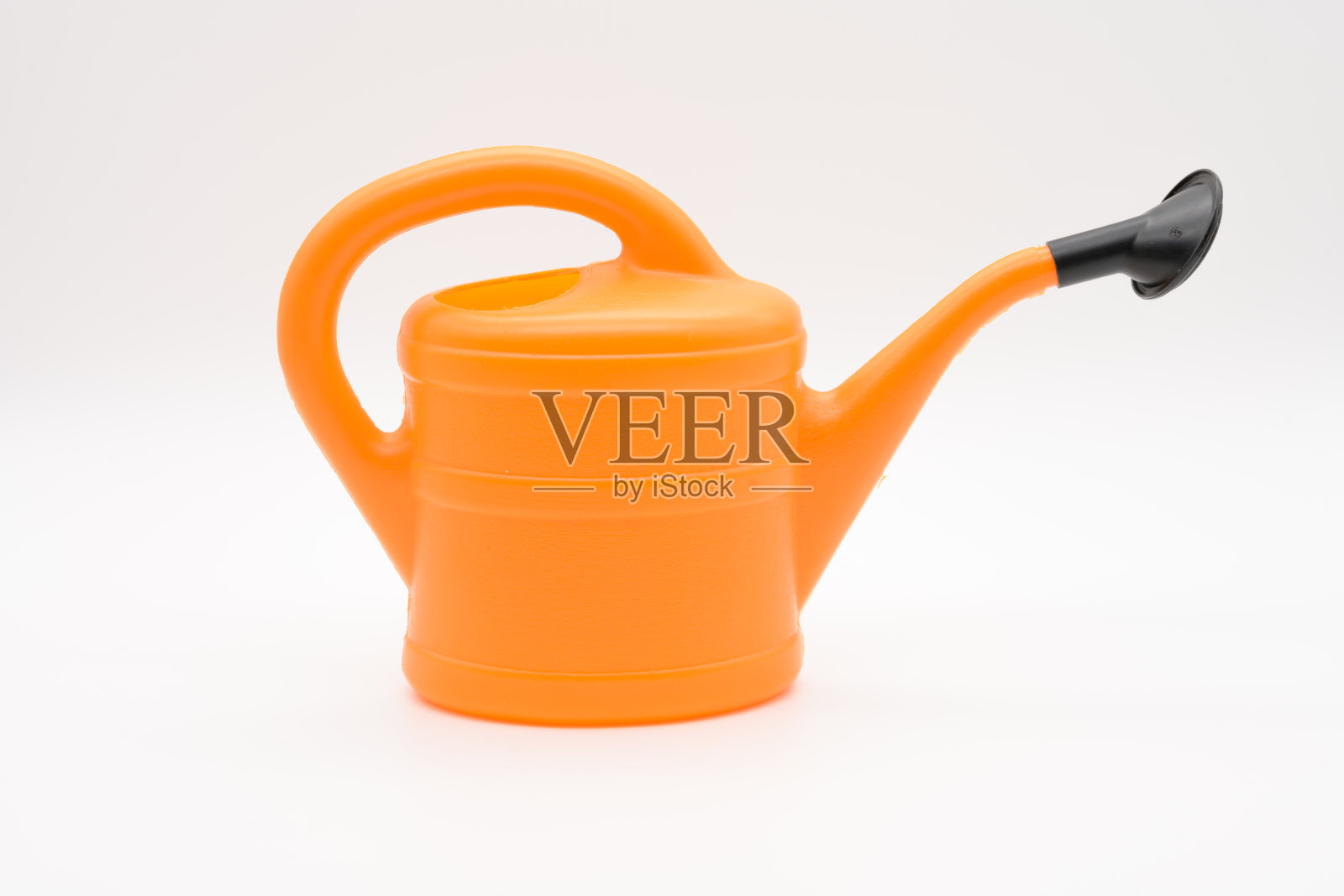 橙色的洒水罐,洒水喷雾被隔离在白色的背景上照片摄影图片