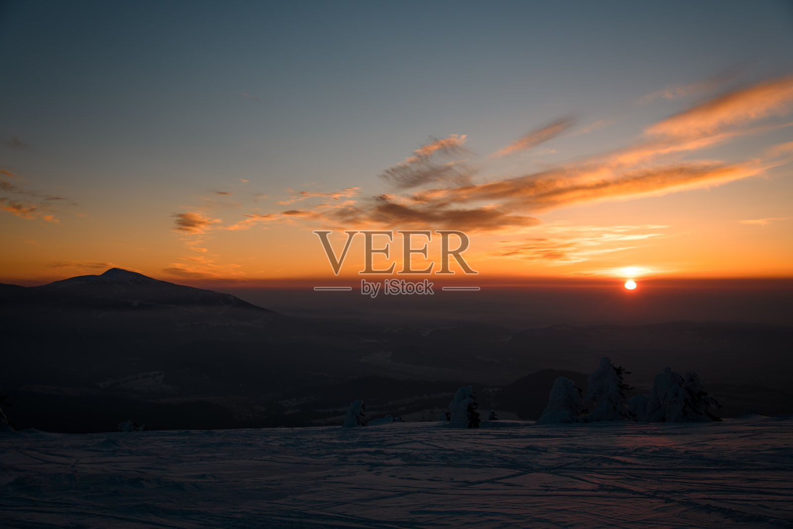 美丽迷人的山景与云杉森林在霜冻的冬天晚上雾和夕阳。照片摄影图片