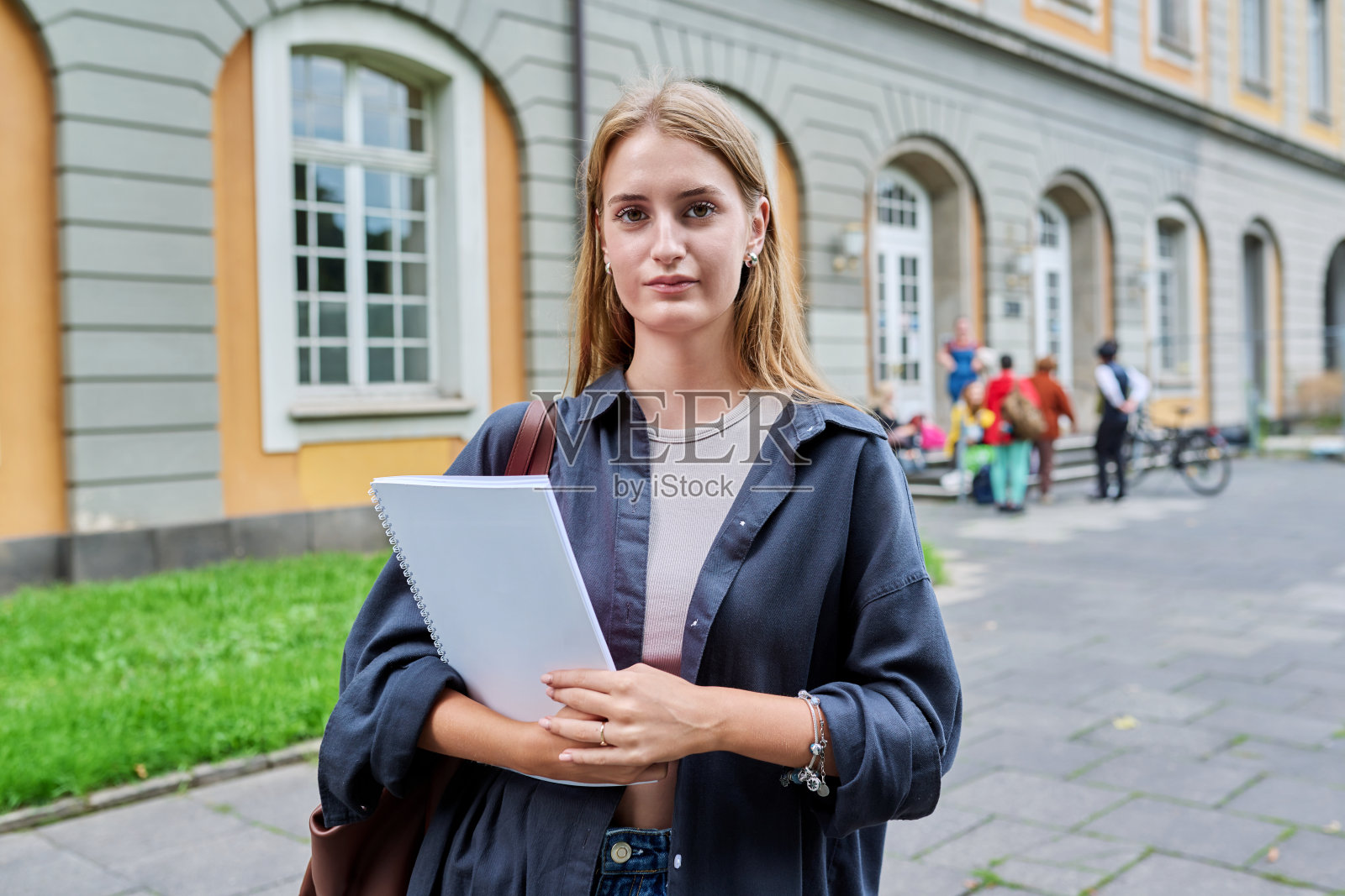 十几岁的女学生在户外摆姿势,教学楼背景照片摄影图片
