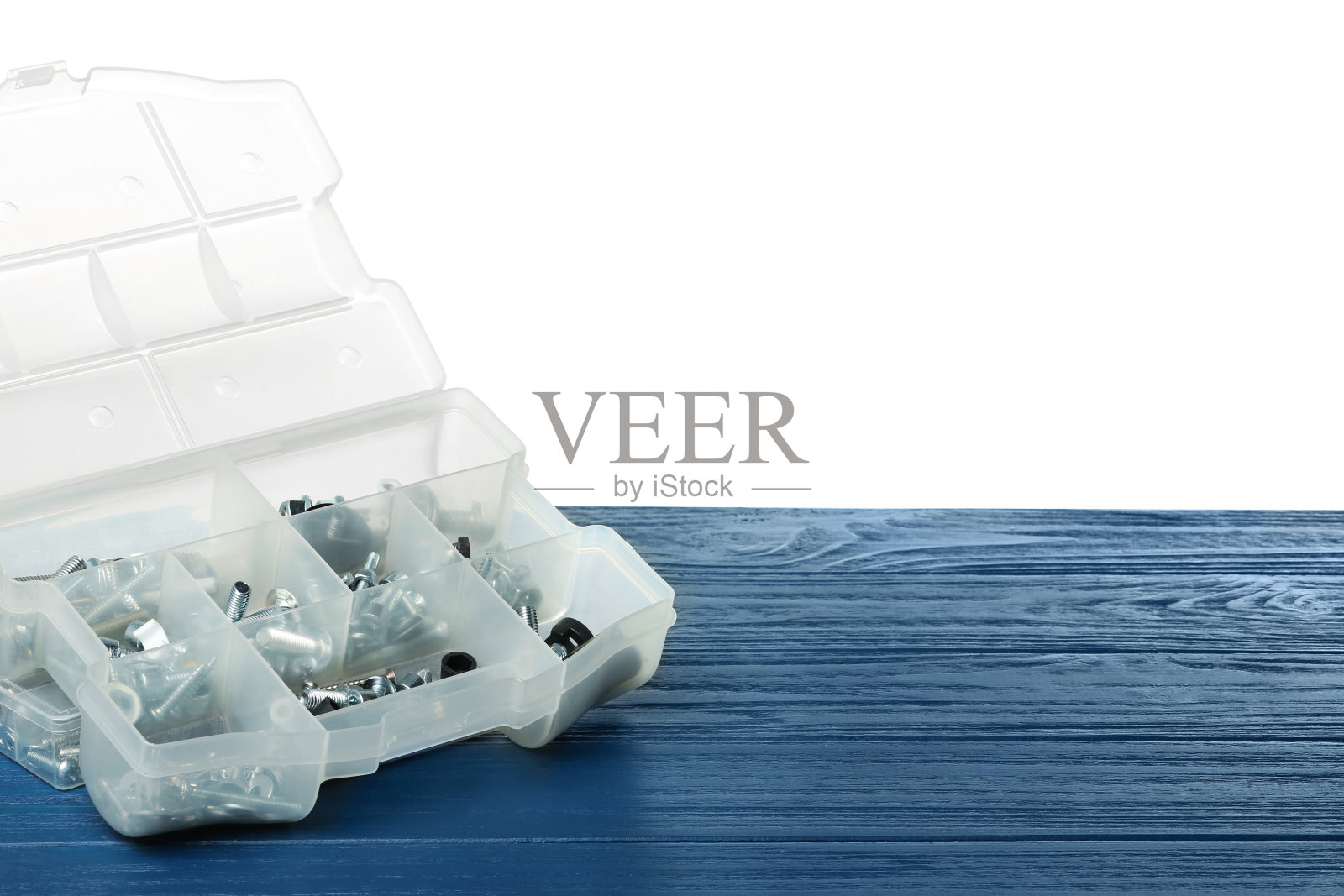 塑料盒与不同的螺栓和螺母在灰色木桌对白色背景照片摄影图片
