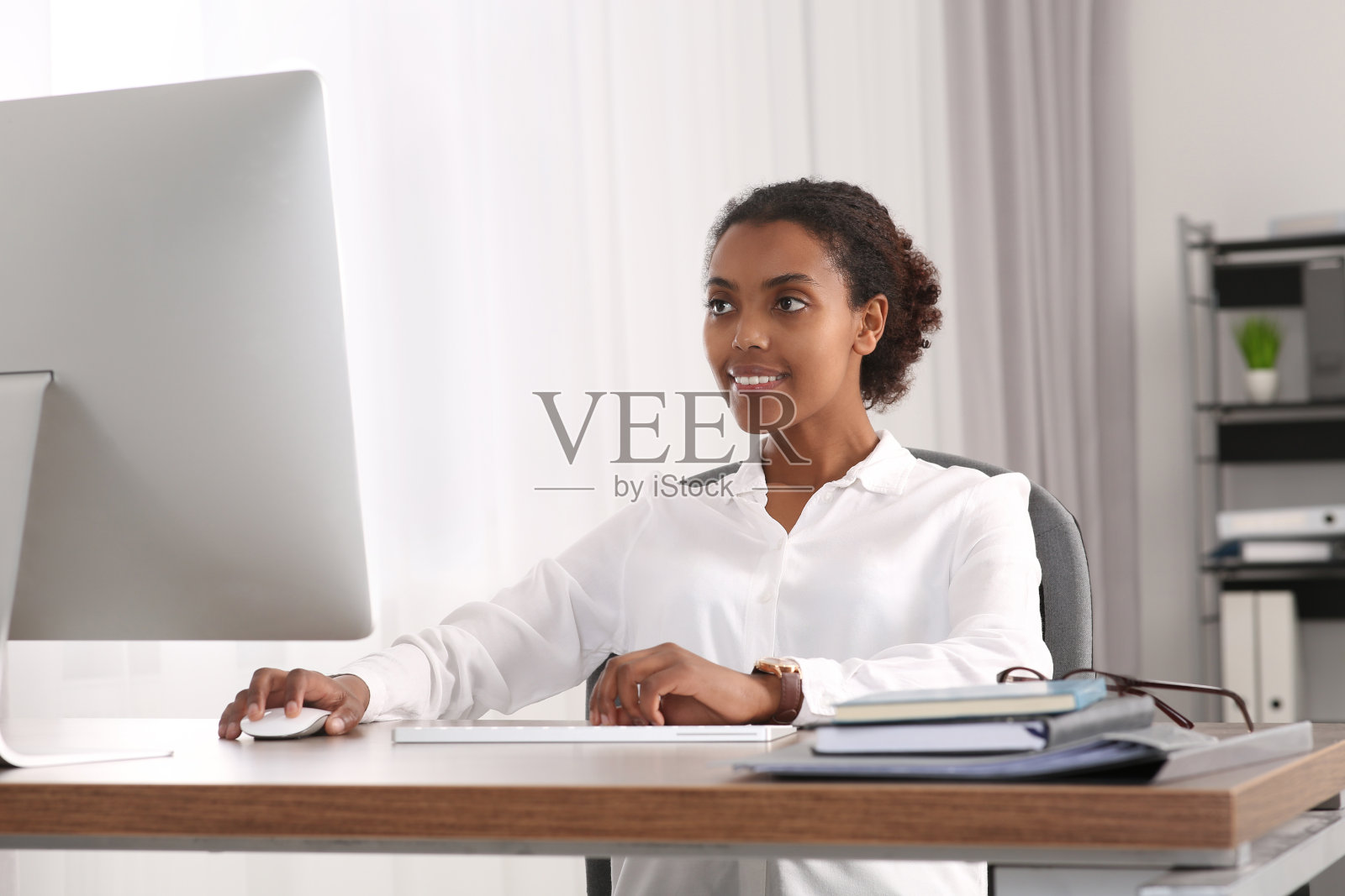 微笑的非裔美国实习生在办公室的桌子上用电脑工作照片摄影图片