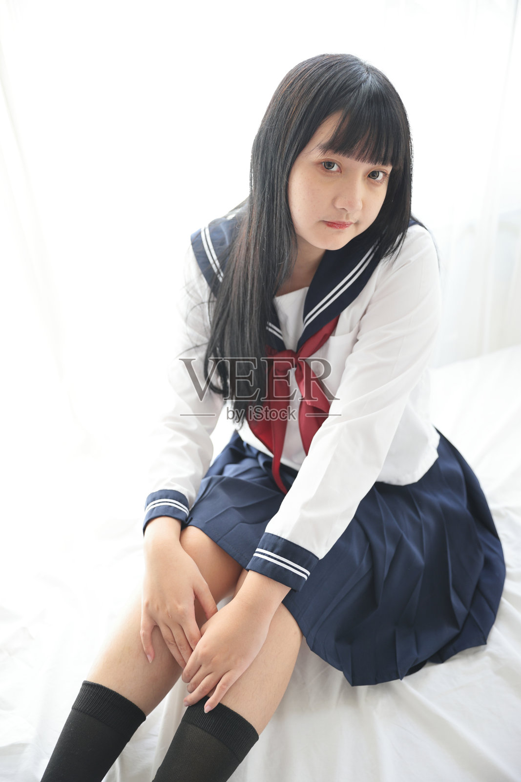 亚洲高中女生坐在白色的房间里看着相机照片摄影图片