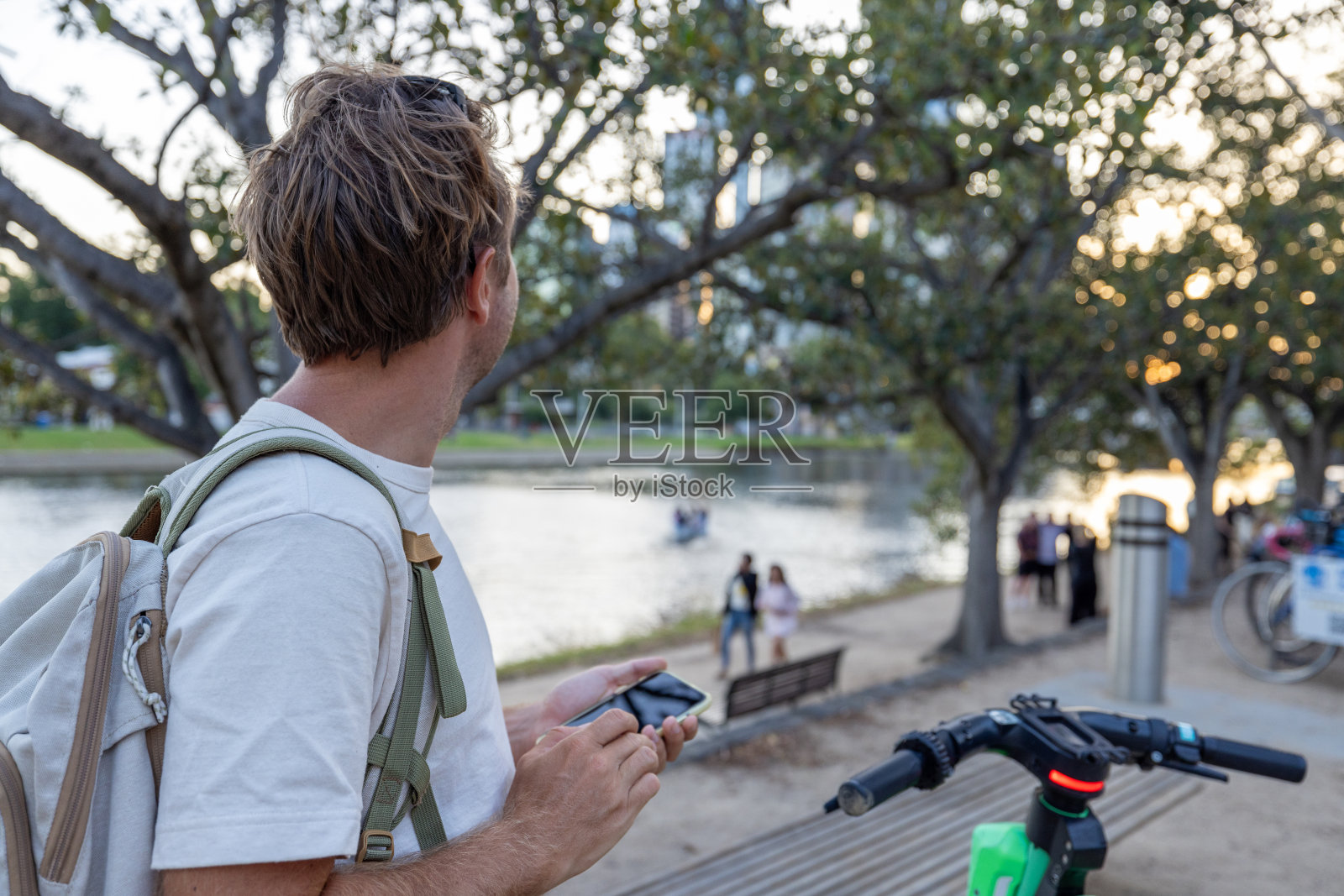 年轻人用手机应用租了一辆电动滑板车照片摄影图片