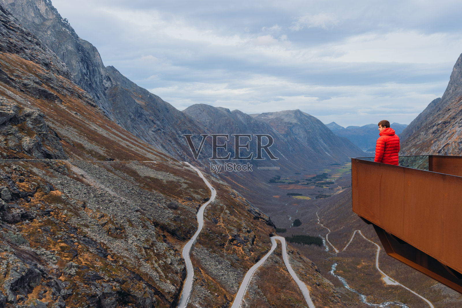 一名男子凝视着挪威特罗尔斯蒂根的发夹路田园诗般的景色照片摄影图片