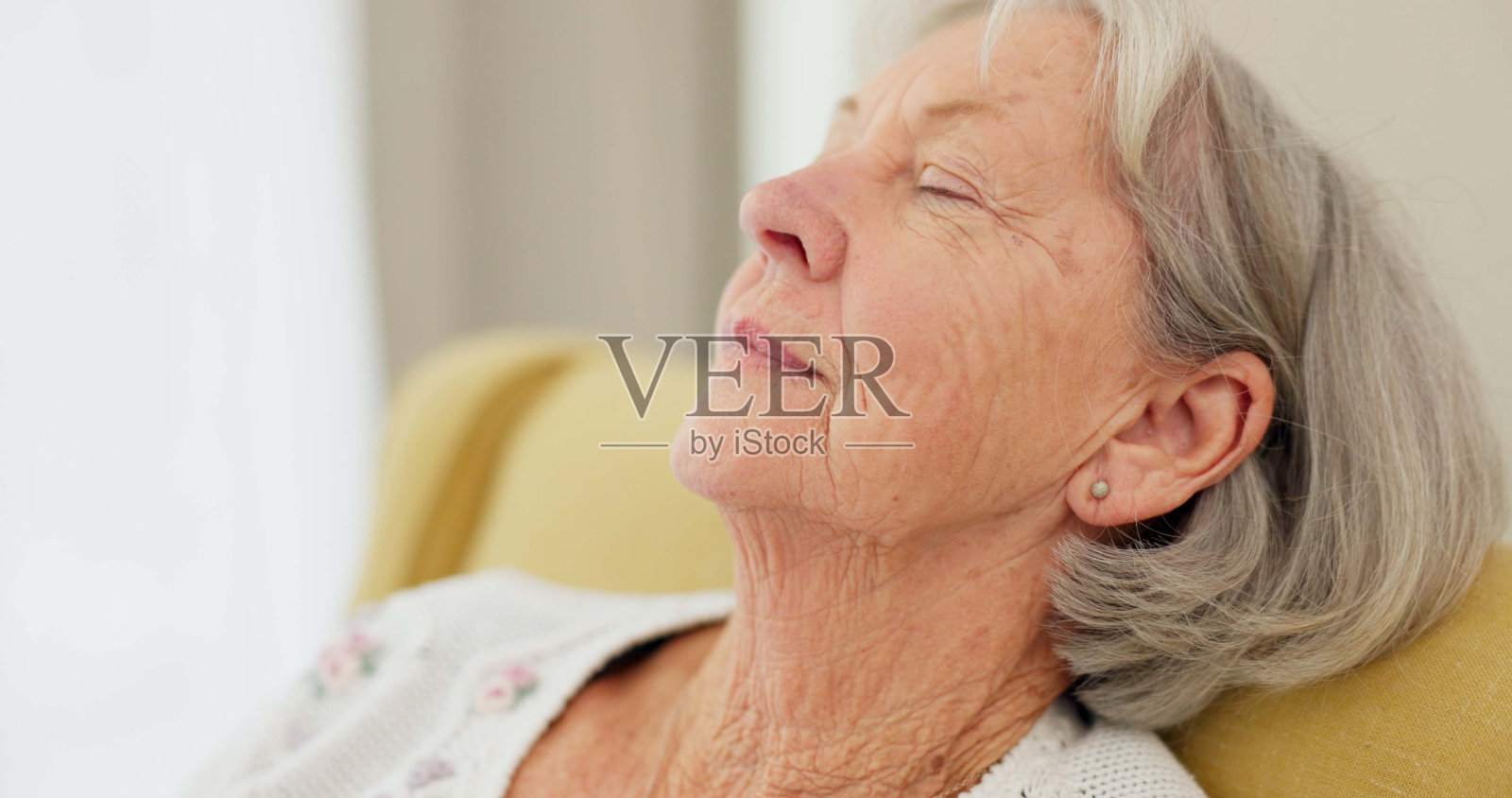 年长女性,在沙发上面部思考,回忆悲伤的记忆,在退休生活中放松。养老院里表情严肃的老年人或老妇人,怀着希望、消极情绪或患有阿尔茨海默病照片摄影图片