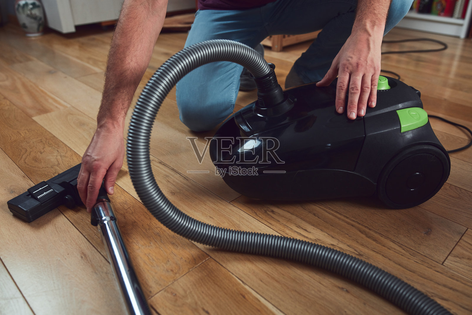男子用吸尘器打扫公寓。照片摄影图片