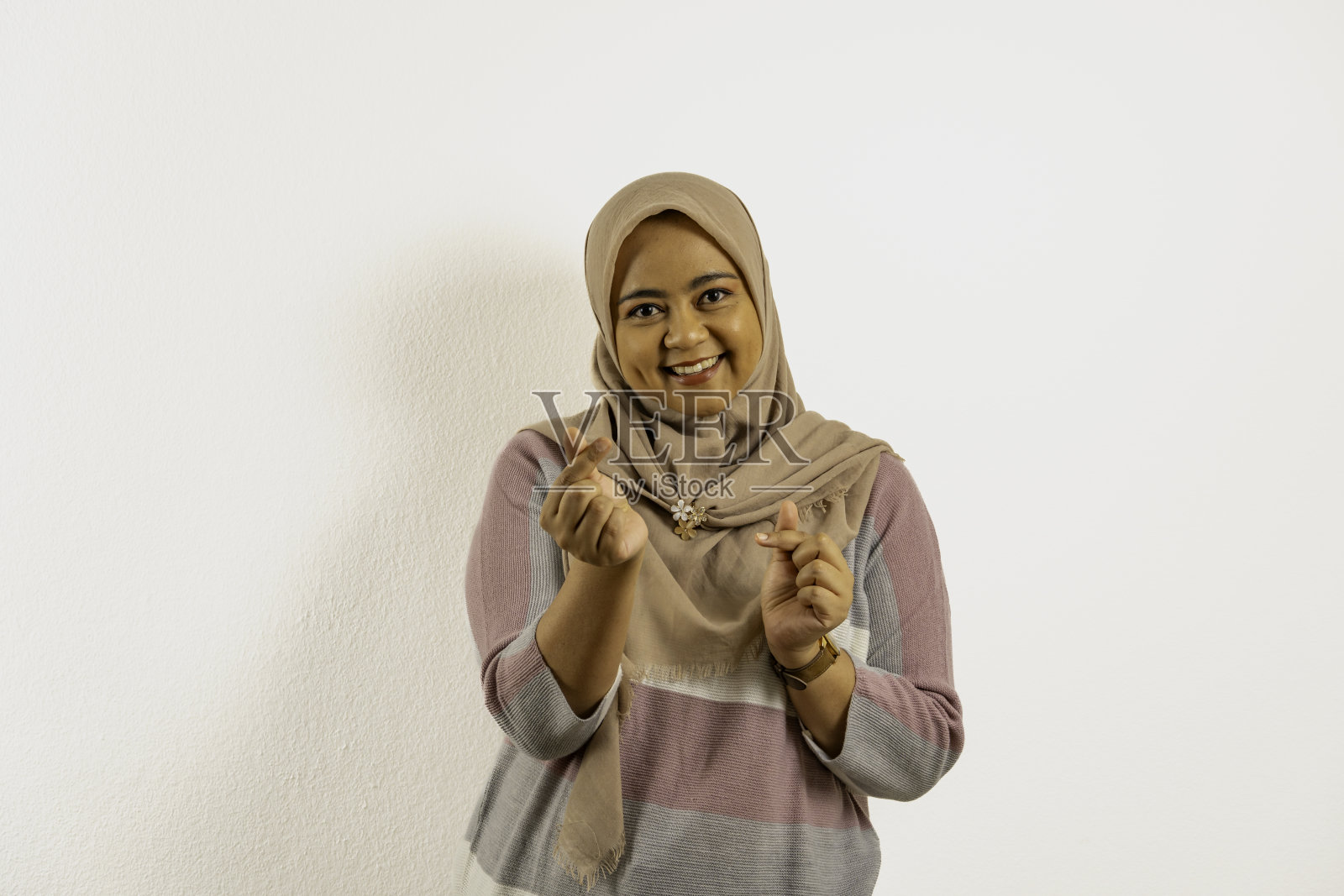 戴着头巾或头巾的亚洲穆斯林妇女微笑着,双手交叉着手指。白色背景的印尼女人。照片摄影图片