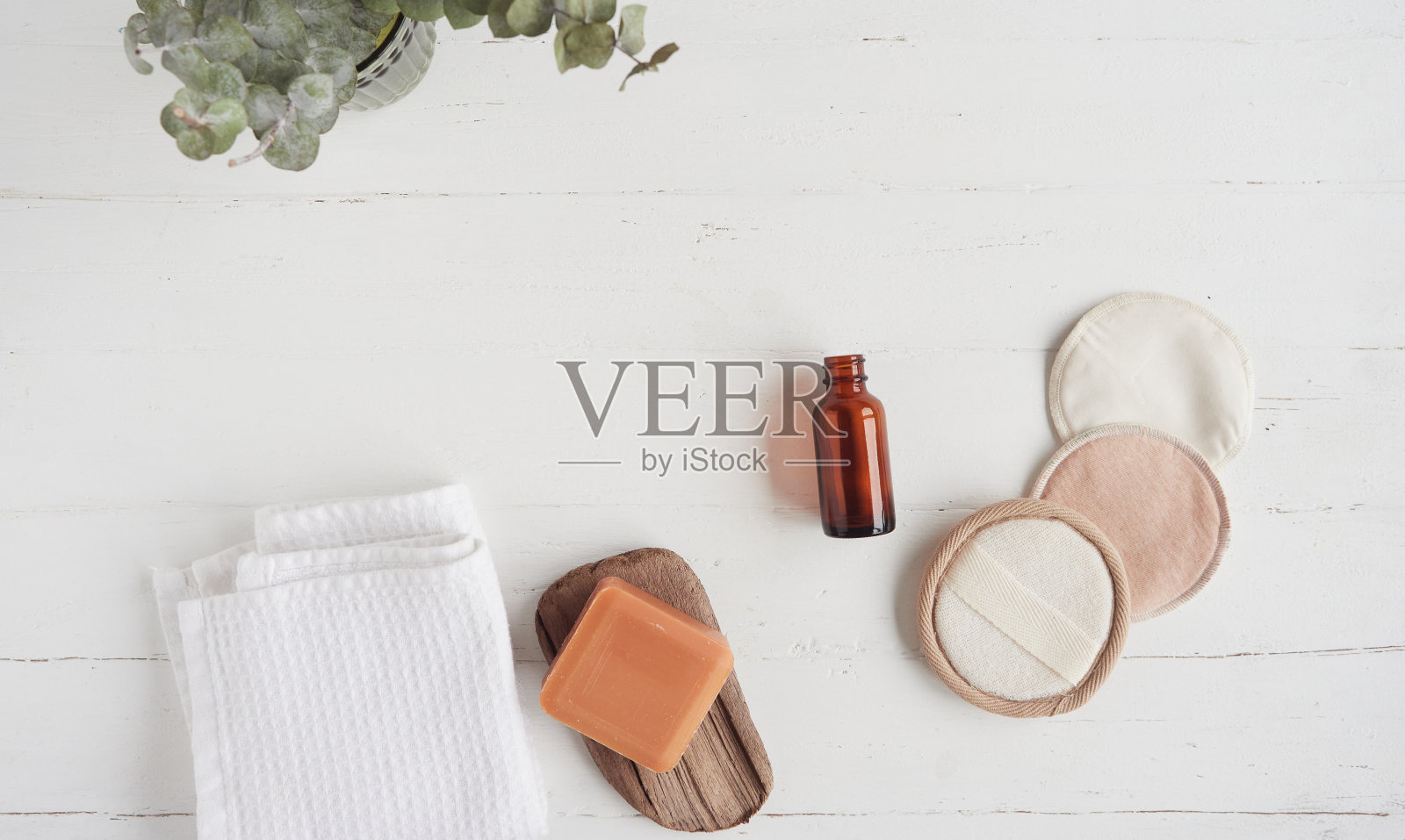 零浪费有机化妆品概念平面布局构图与复制空间。可重复使用卸妆片、有机肥皂、面霜、玻璃瓶、白毛巾和干桉树叶。照片摄影图片