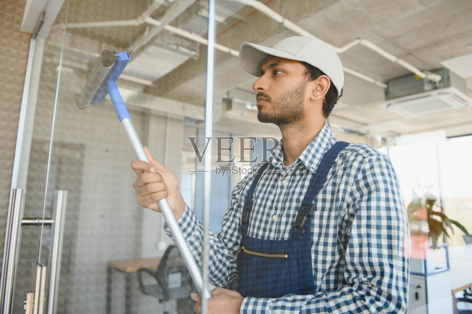 印度男性专业清洁服务工人用专用设备清洁商店的窗户和橱窗照片摄影图片