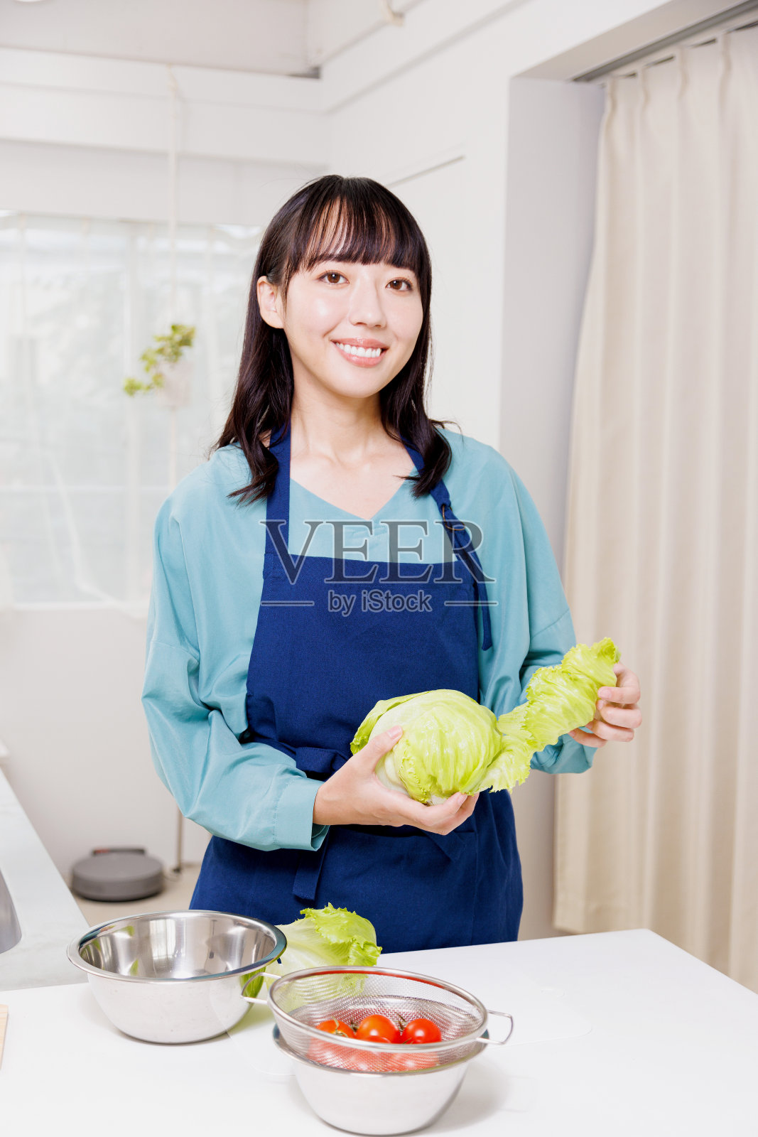 在厨房里吃生菜的亚洲女人照片摄影图片