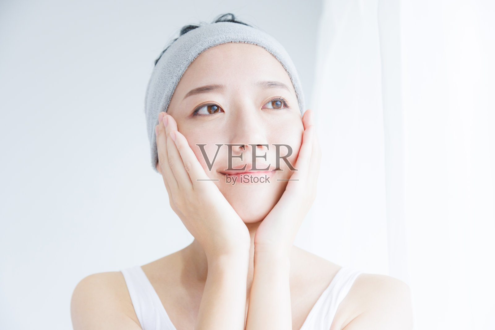 年轻的亚洲女人抚摸着她的脸照片摄影图片