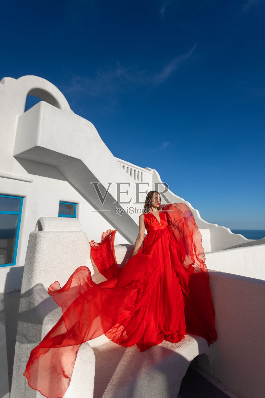 魅力的照片。女孩在大海的背景下挥舞着一件飘逸的红色连衣裙照片摄影图片