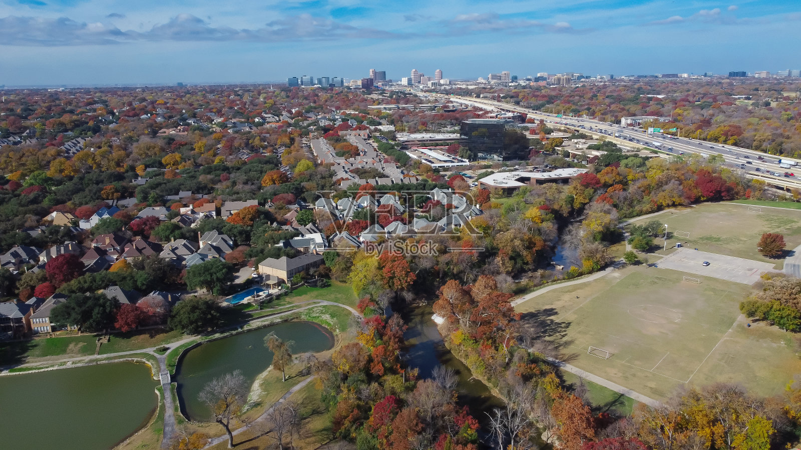 五彩缤纷的秋叶在公园中央与豪华的湖畔住宅,足球场,白石溪附近的主要高速公路北达拉斯,德克萨斯州,富裕的社区空中照片摄影图片