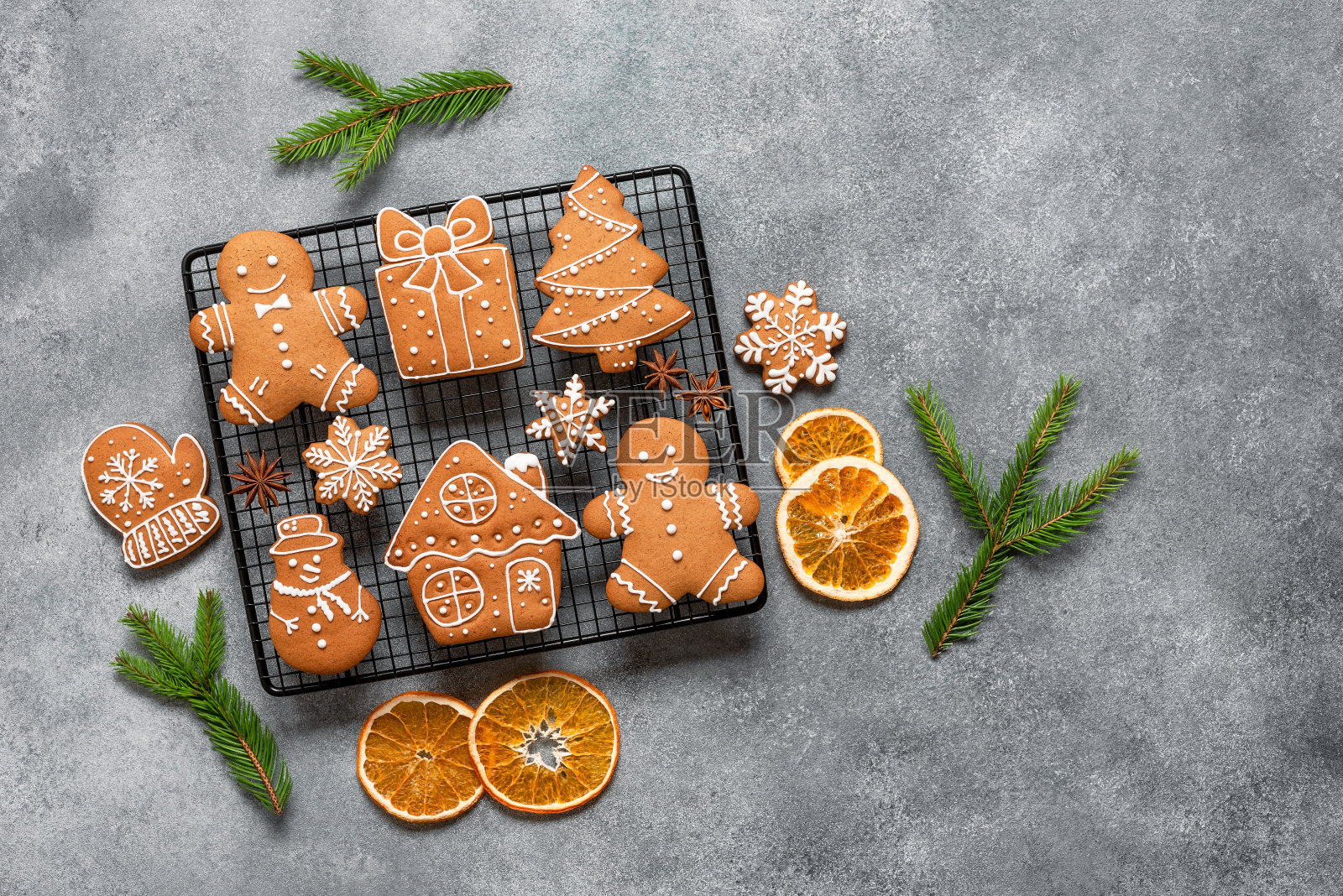 各种圣诞姜饼饼干装饰冷杉枝和橙片,灰色混凝土背景。俯视图,平面布局,文本空间。照片摄影图片