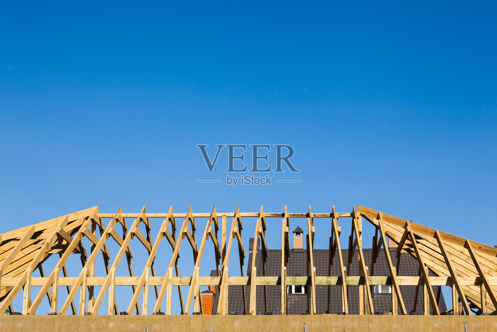 建造新私人住宅的屋顶。新木梁安装在房子的屋顶上。照片摄影图片