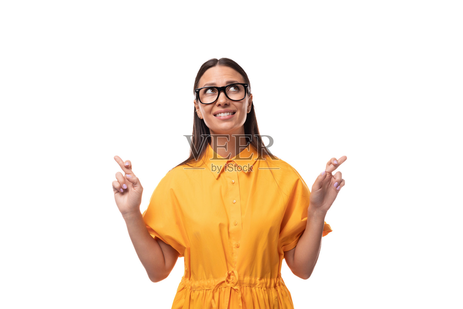 年轻的黑发女子戴着眼镜,穿着橙色的夏装,交叉着手指,期待着照片摄影图片