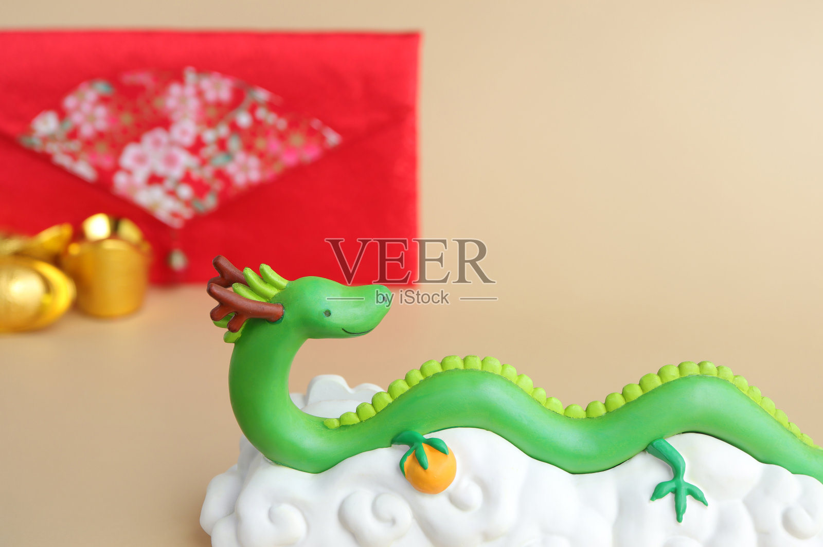 浅棕色背景下的春节绿龙雕像和红包。2024年新年。照片摄影图片